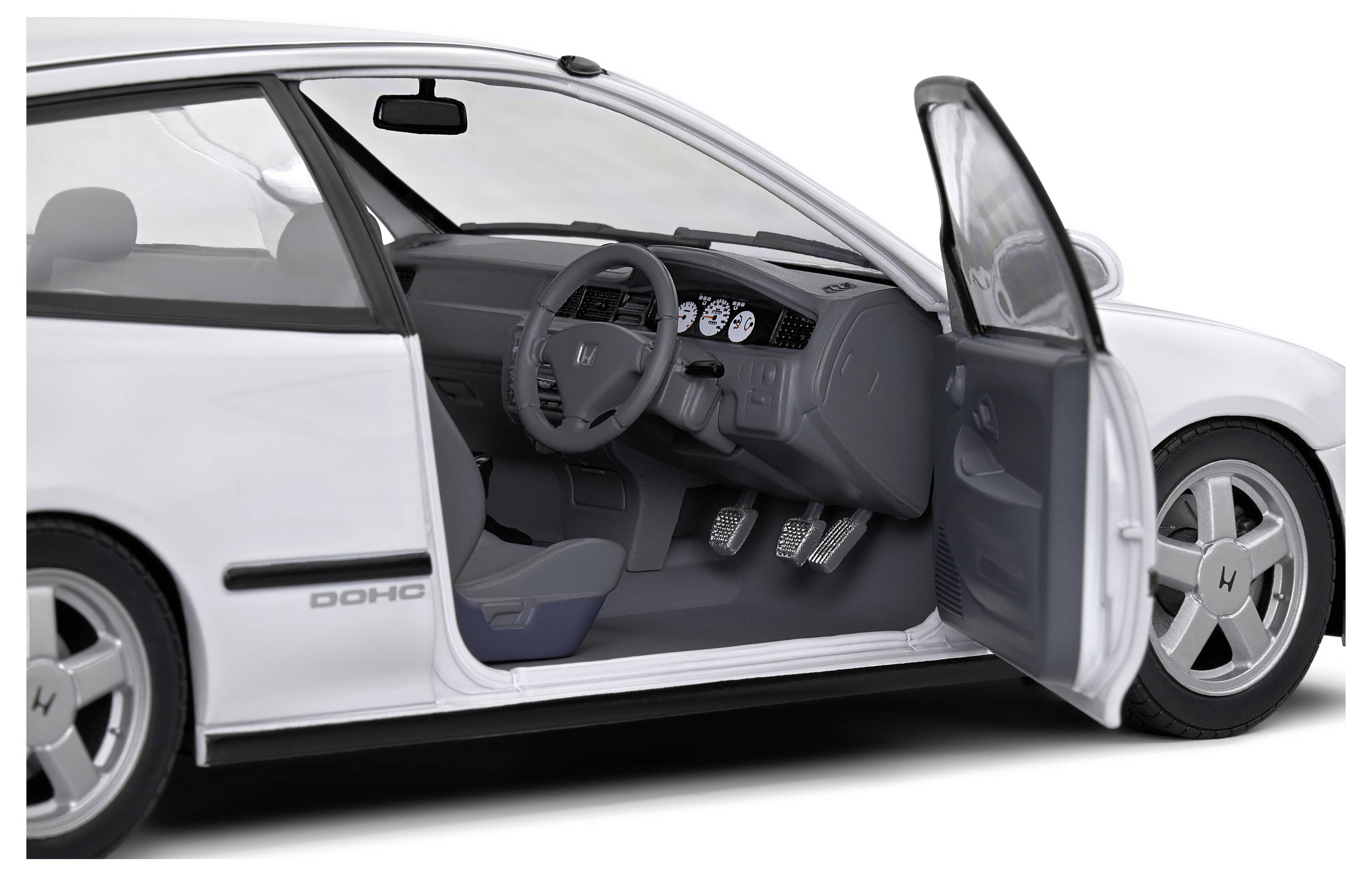 Białe auto z otwartymi drzwiami kierowcy prezentuje wnętrze i deskę rozdzielczą.