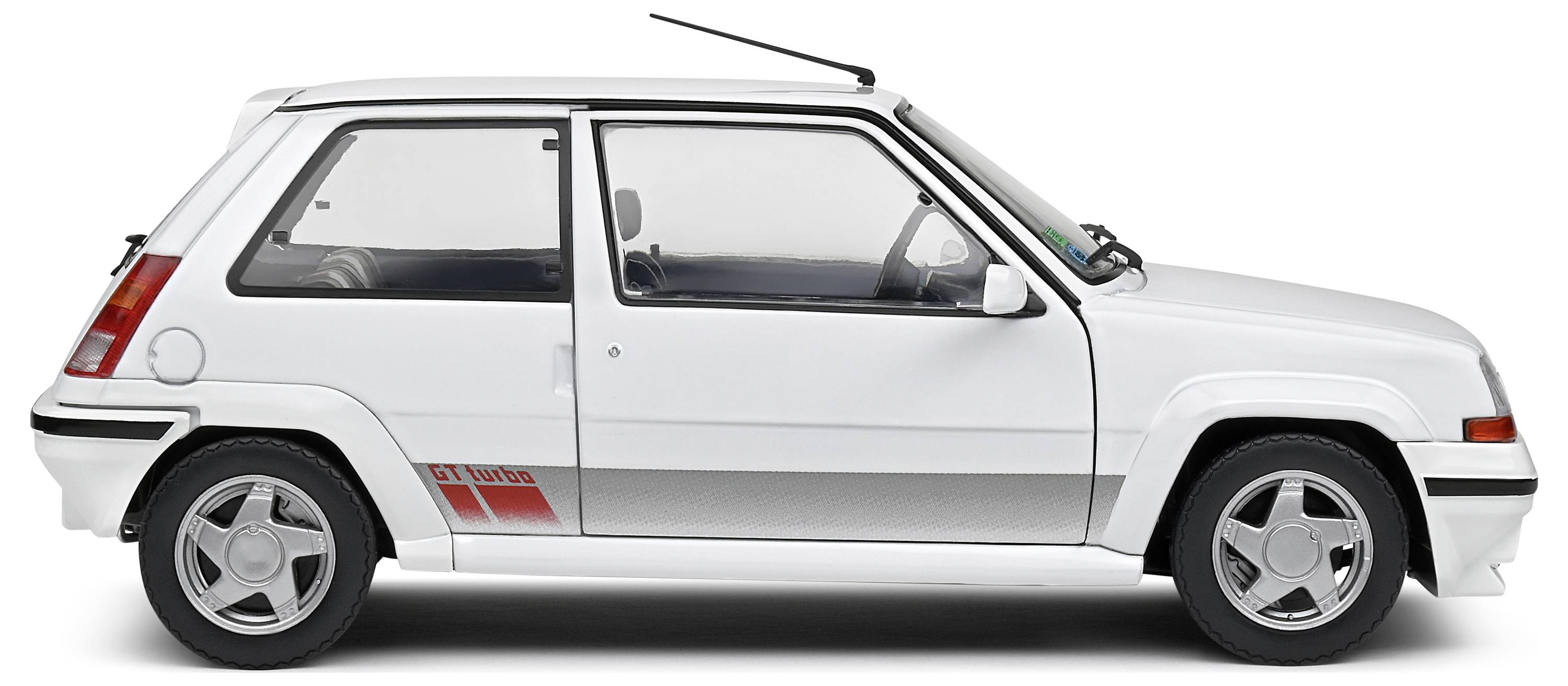 Białe auto z trzema drzwiami, o sportowym wyglądzie, z charakterystycznymi naklejkami GT Turbo na boku. Ujęcie z profilu na neutralnym tle.