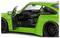 Zielony samochód sportowy z otwartymi drzwiami, prezentujący sportowe wnętrze z kierownicą i deską rozdzielczą. Marka samochodu widoczna na oponach.