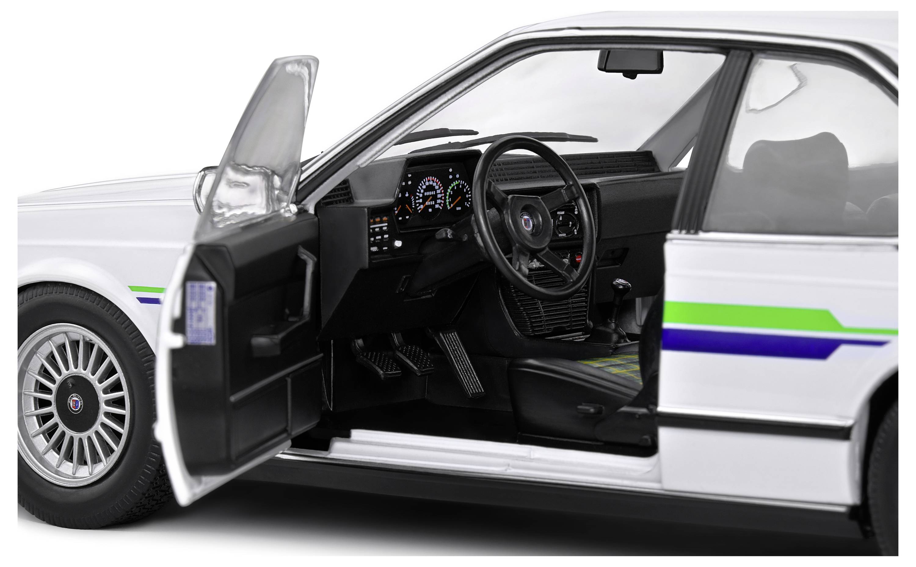 Białe auto z otwartymi drzwiami kierowcy ukazuje wnętrze. Widoczne są kierownica, deska rozdzielcza i fotel kierowcy.