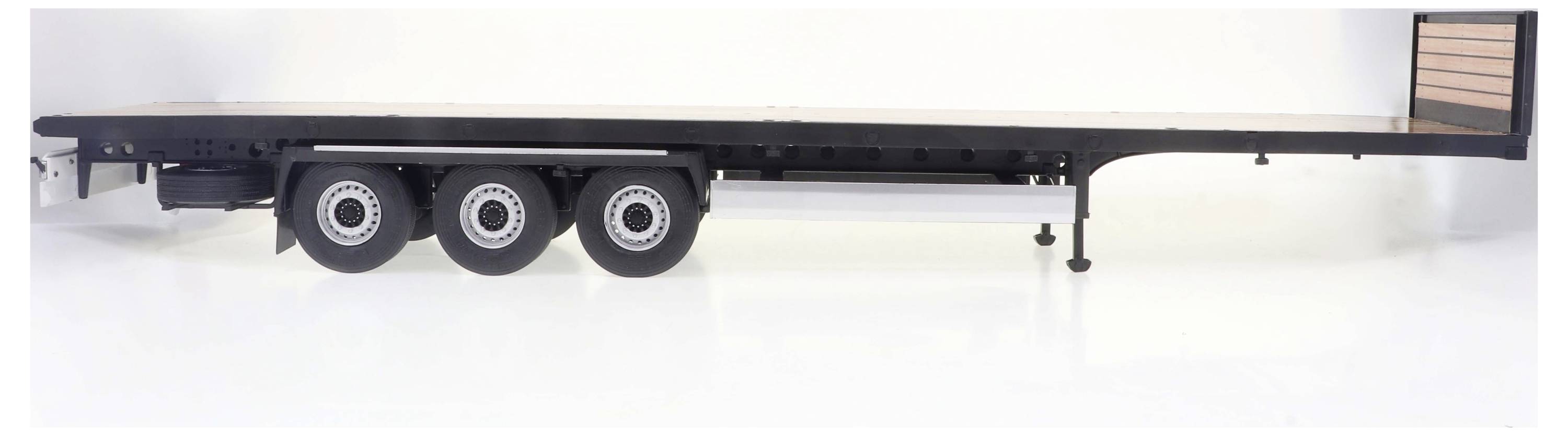 Widok z boku przyczepy ciężarowej z trzema osiami, odpowiedniej do transportu dużych i ciężkich ładunków.