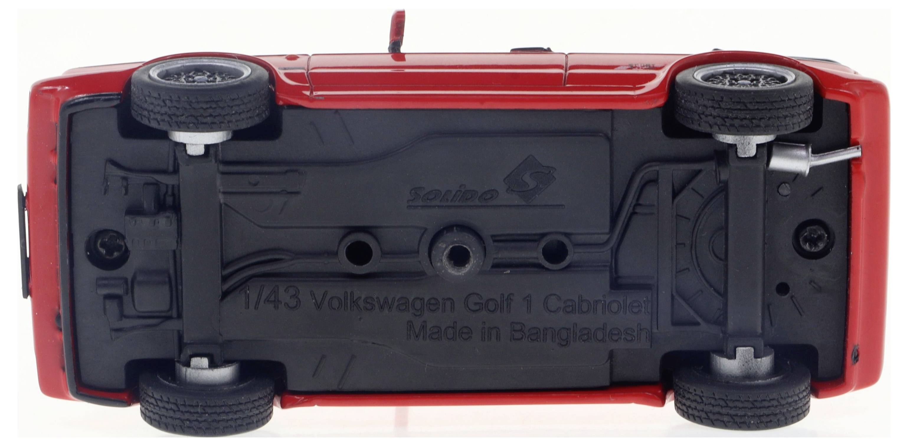 Czerwony samochodzik zabawkowy odwrócony spodem do góry z napisem 'Volkswagen Golf 1 Cabrio, Made in Bangladesh' na spodzie.