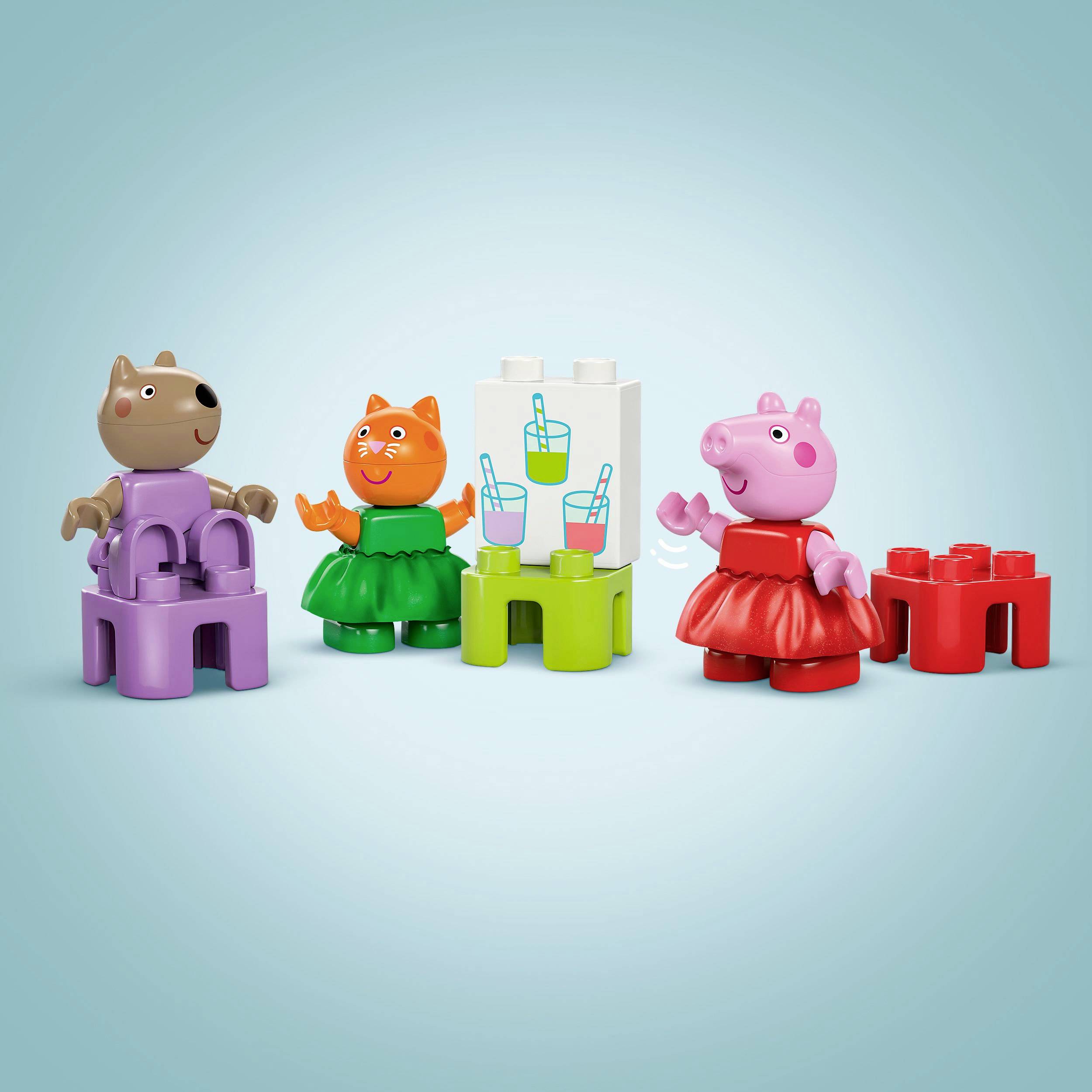 Trzy kolorowe figurki, w tym różowa świnka w czerwonej sukience, bawią się klockami przed jasnoniebieską ścianą.