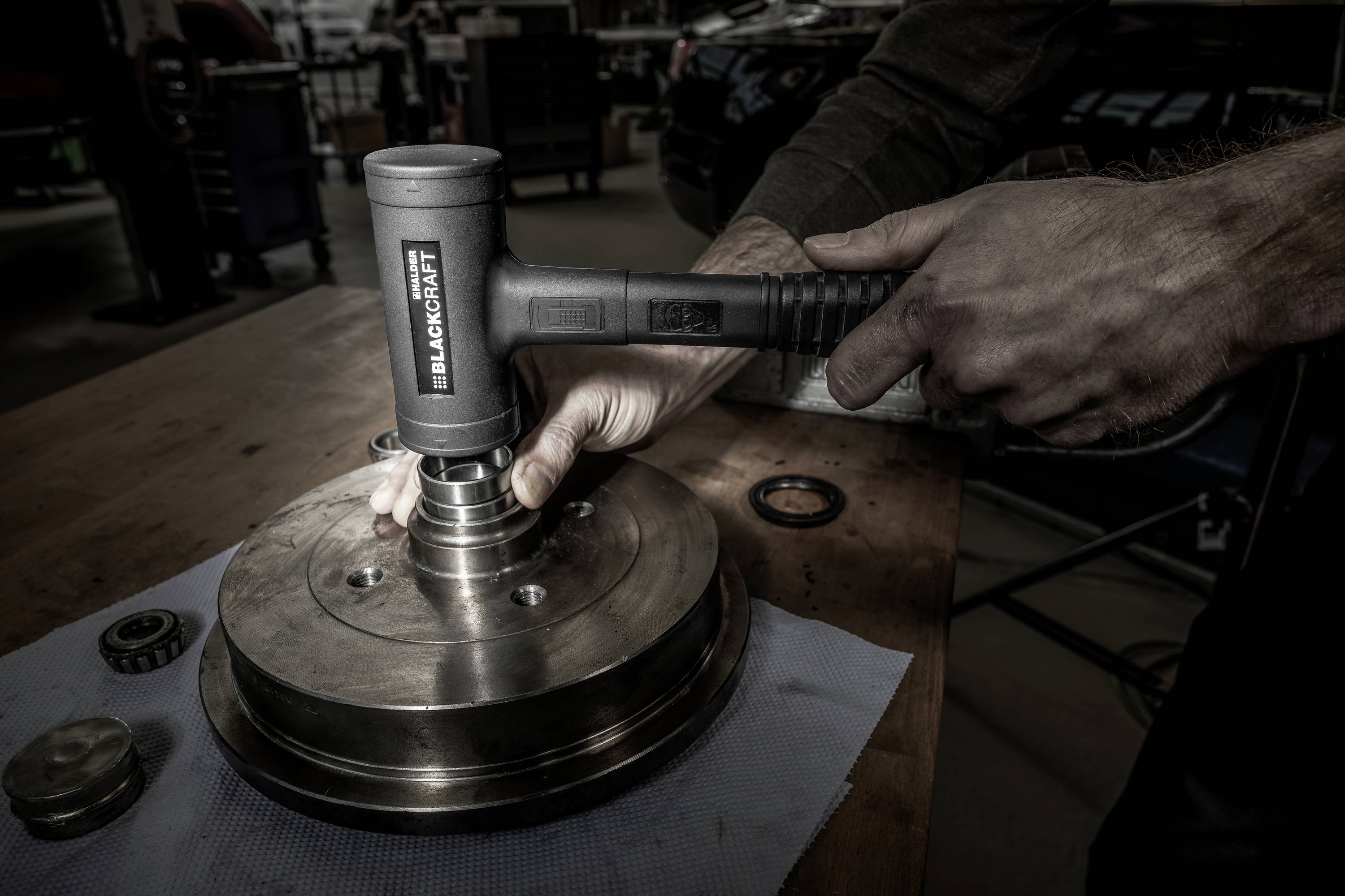 Osoba naprawia w warsztacie metalowy element za pomocą narzędzia. Otoczenie jest przemysłowe.