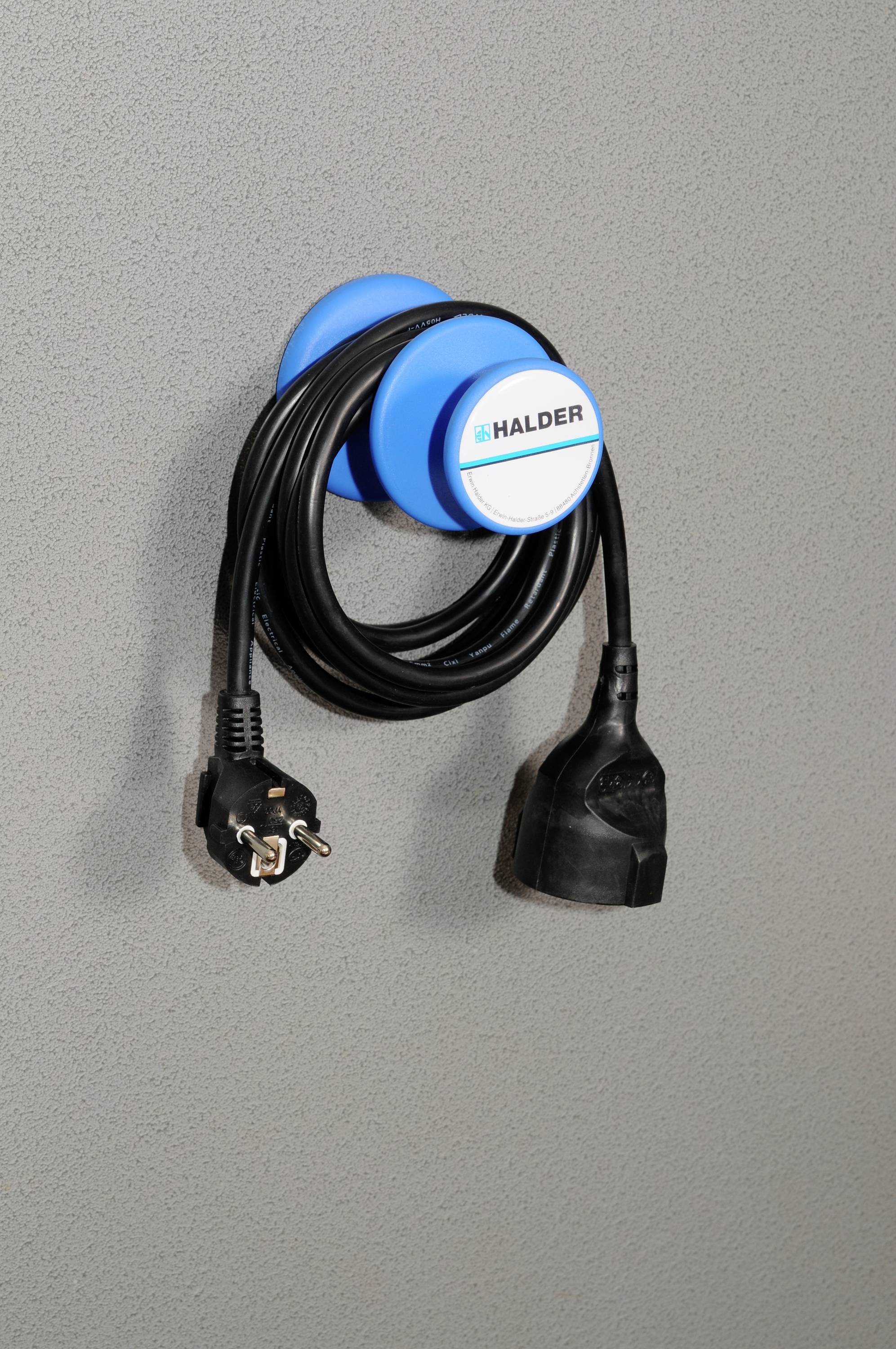 Czarny kabel z dwoma wtyczkami wisi starannie na niebieskim uchwycie na ścianie.