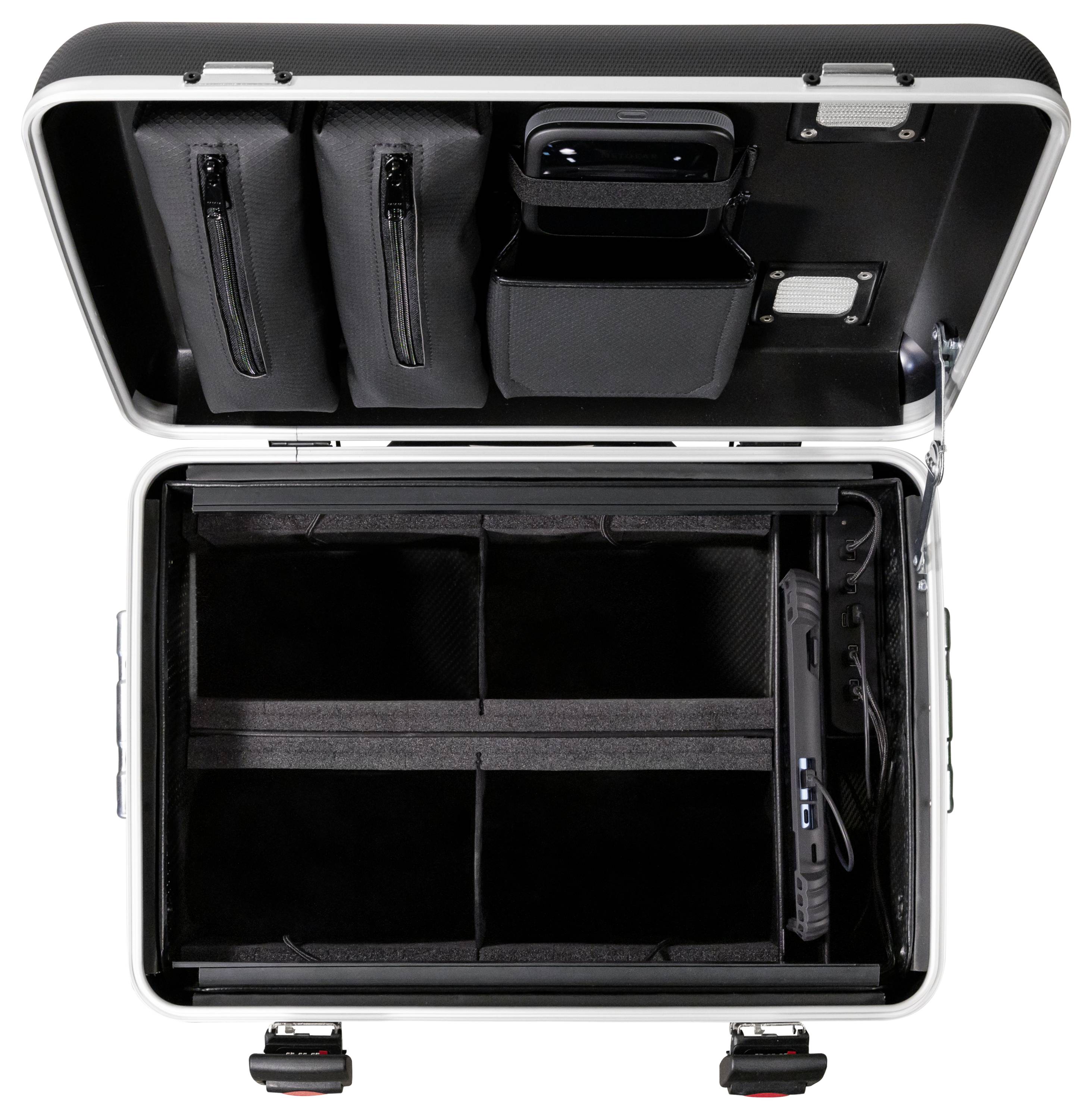 Otwarty czarny kufer z wieloma przegródkami i kieszeniami w pokrywie, odpowiedni do zorganizowanego przechowywania urządzeń elektronicznych i akcesoriów.