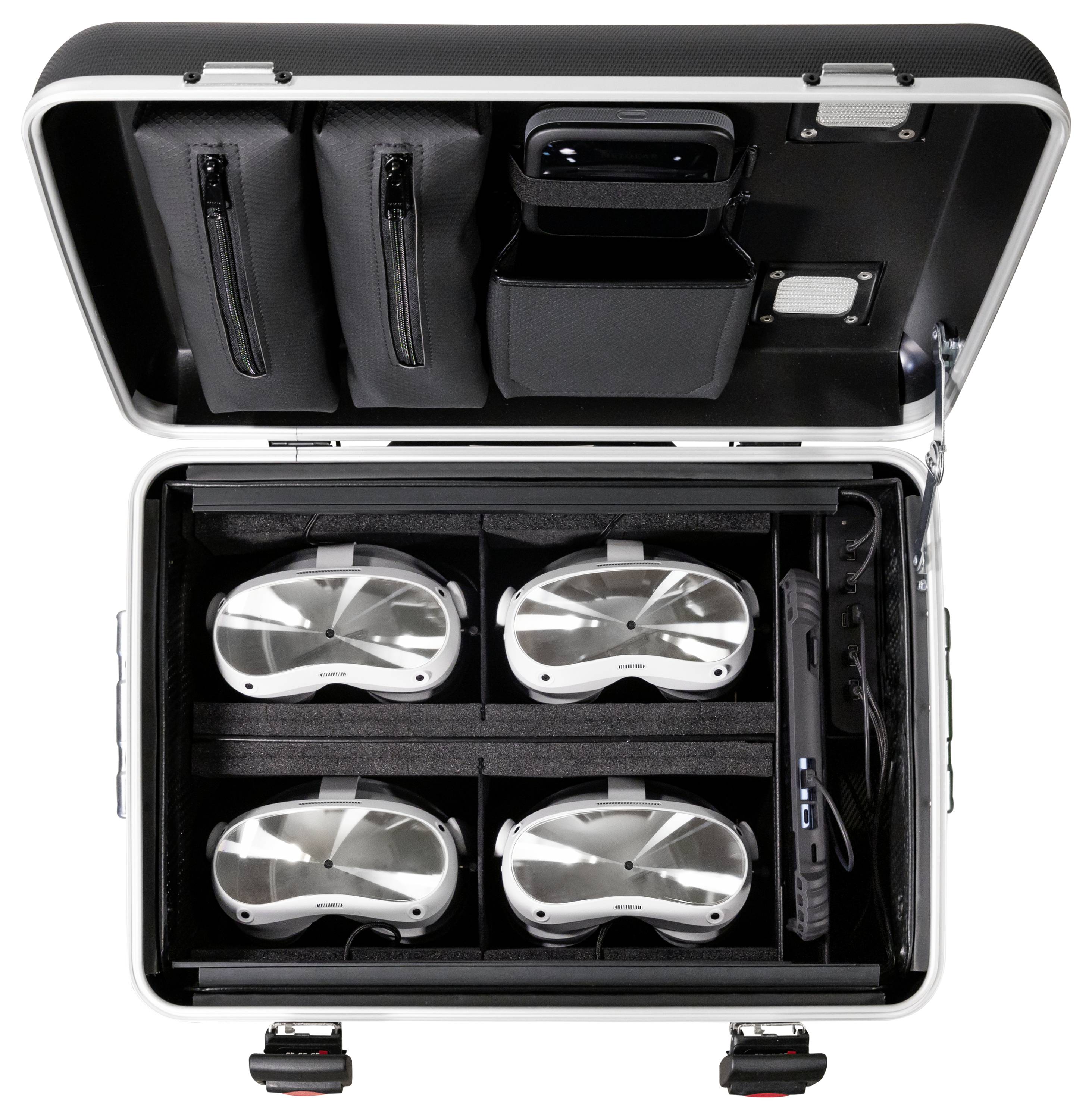 Otwarty kufer z czterema goglami VR, starannie ułożonymi w przegródkach, otoczony torbami z akcesoriami, gotowy do transportu.