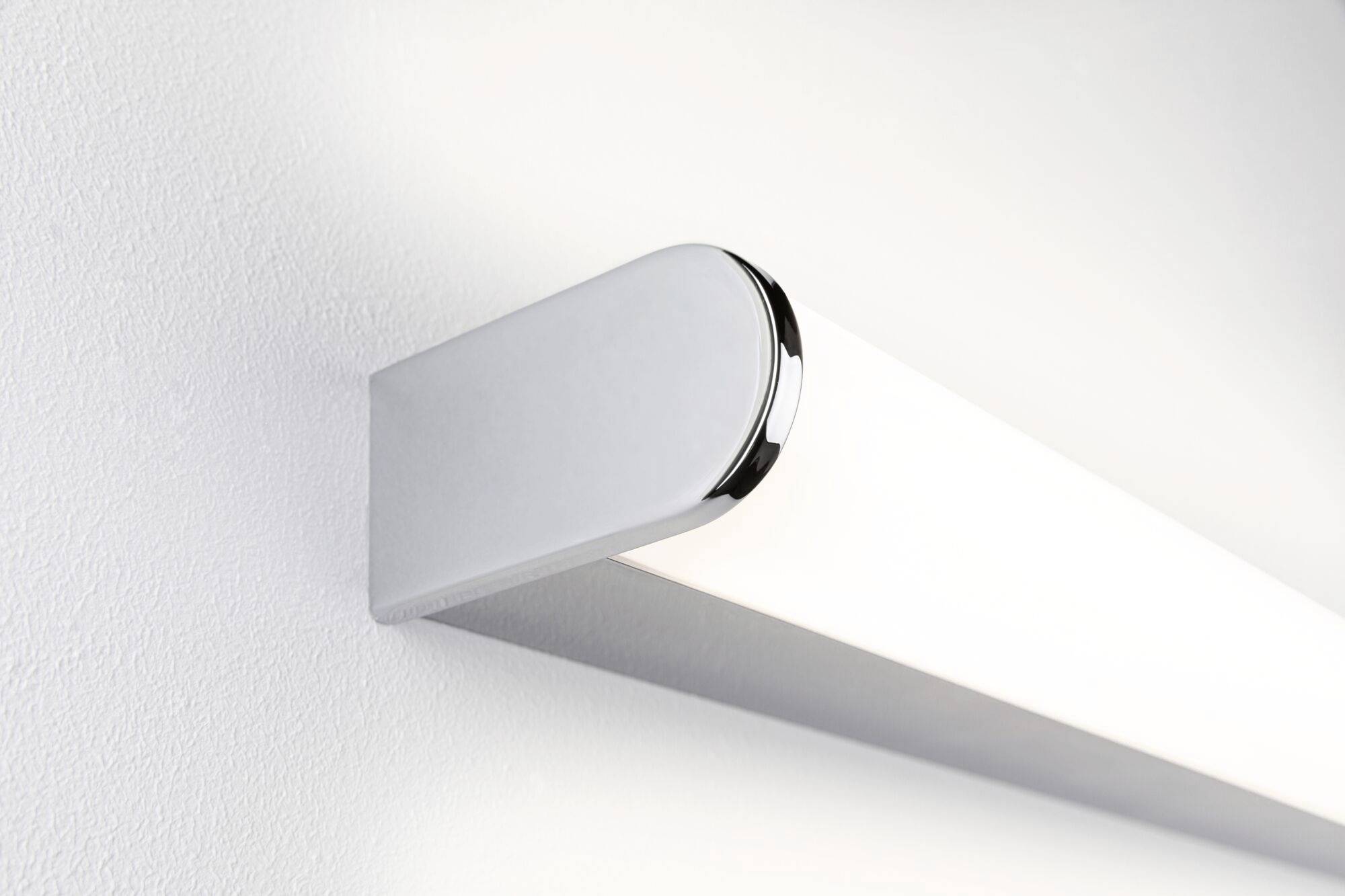 Nowoczesna, podłużna lampa LED zamontowana na białej ścianie, emituje jasne, równomierne światło. Idealna do minimalistycznych wnętrz.