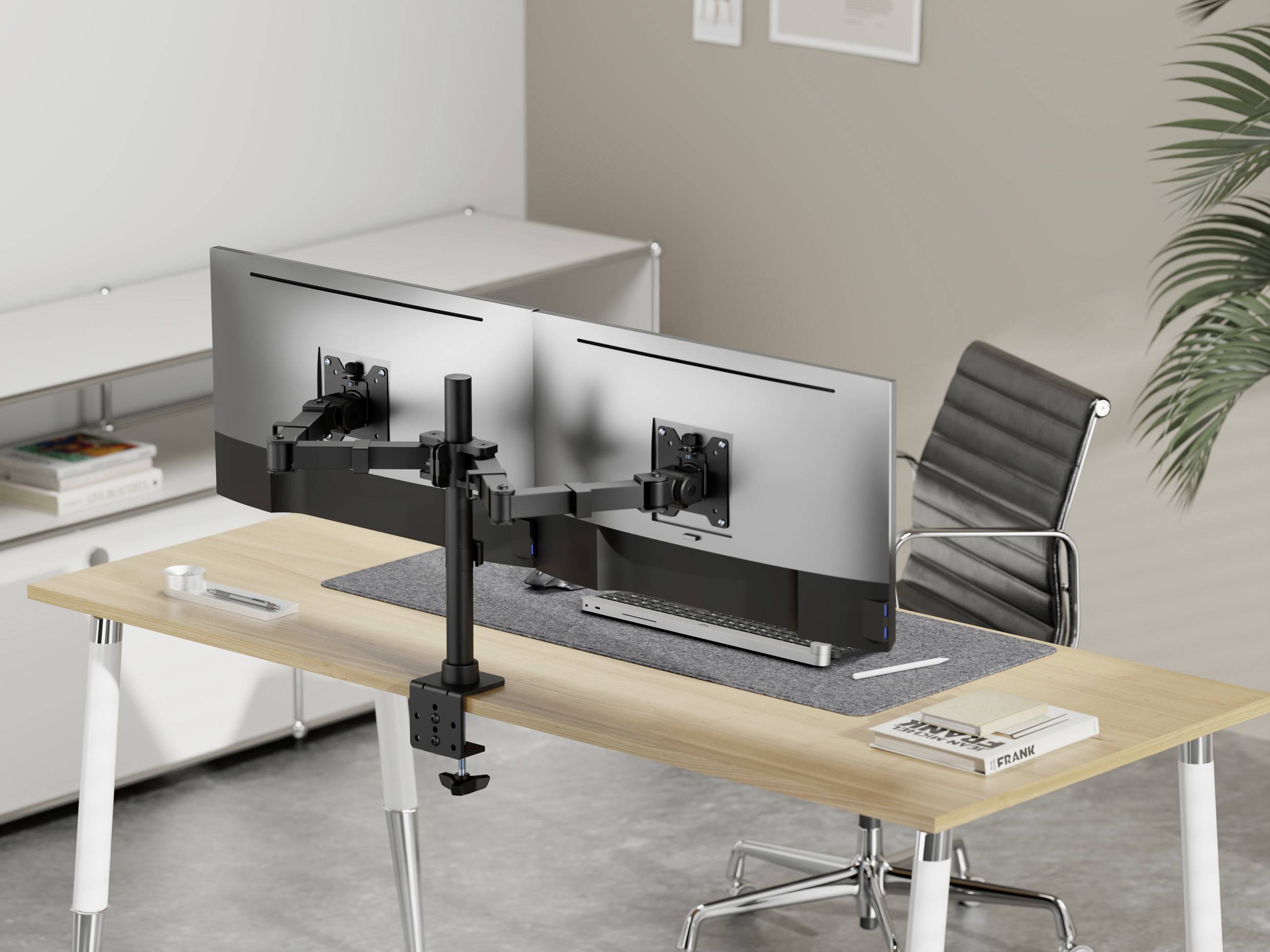 Nowoczesne biurko z dwoma dużymi monitorami na podstawce, ergonomicznym fotelem i minimalistycznym wyposażeniem.