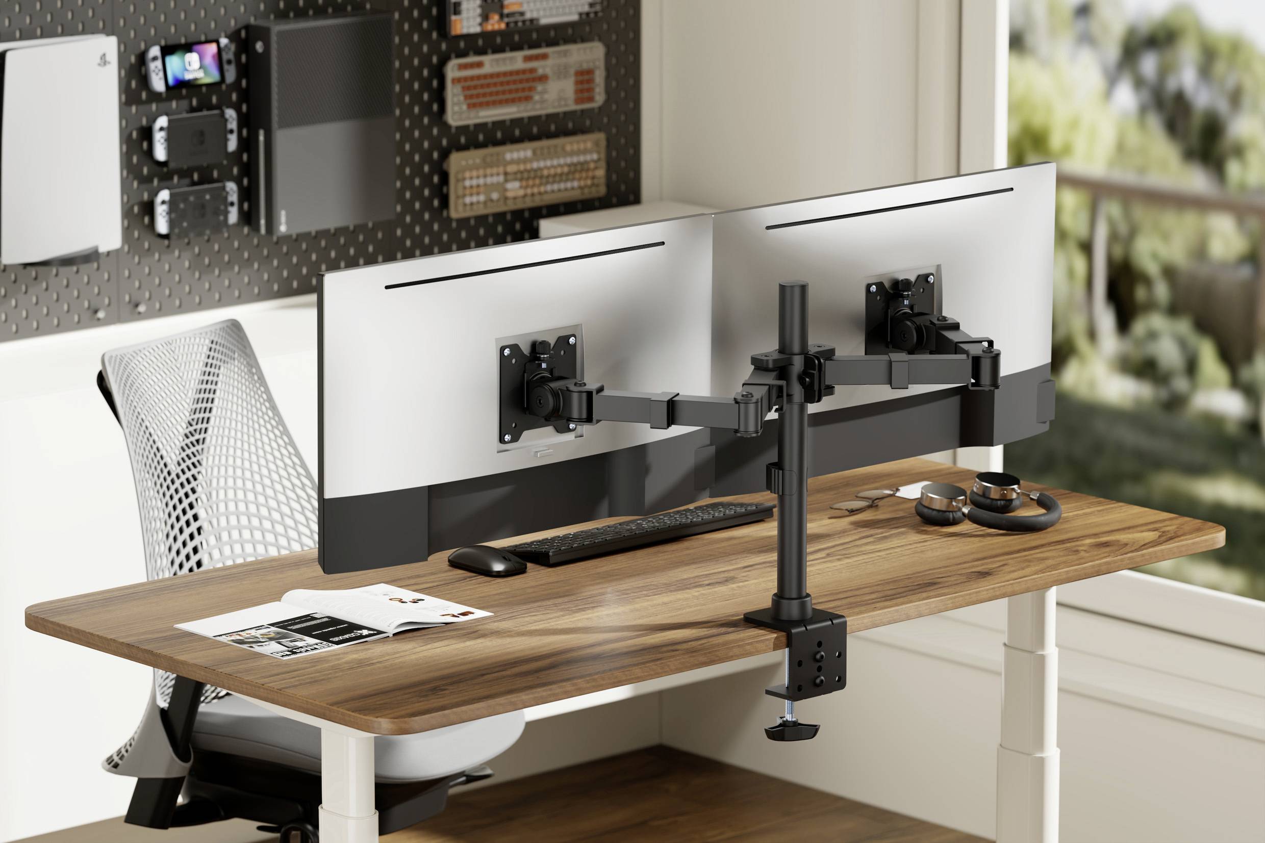 Biurko z dwoma monitorami na uchwytach, klawiaturą, myszą i podstawką pod laptopa. W tle widać okno z widokiem na zewnątrz.