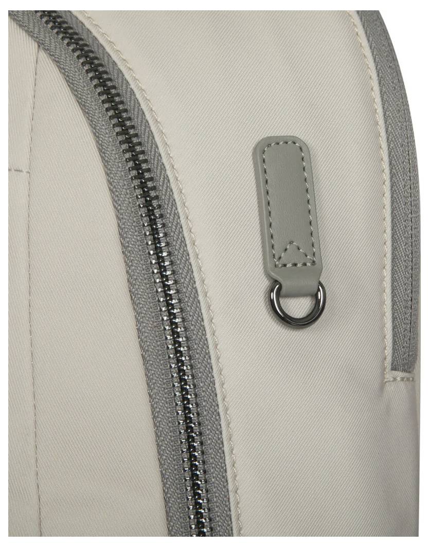 Fragment beżowego plecaka z szarym zamkiem błyskawicznym i metalową pętlą przy małym szarym skórzanym zawieszce.