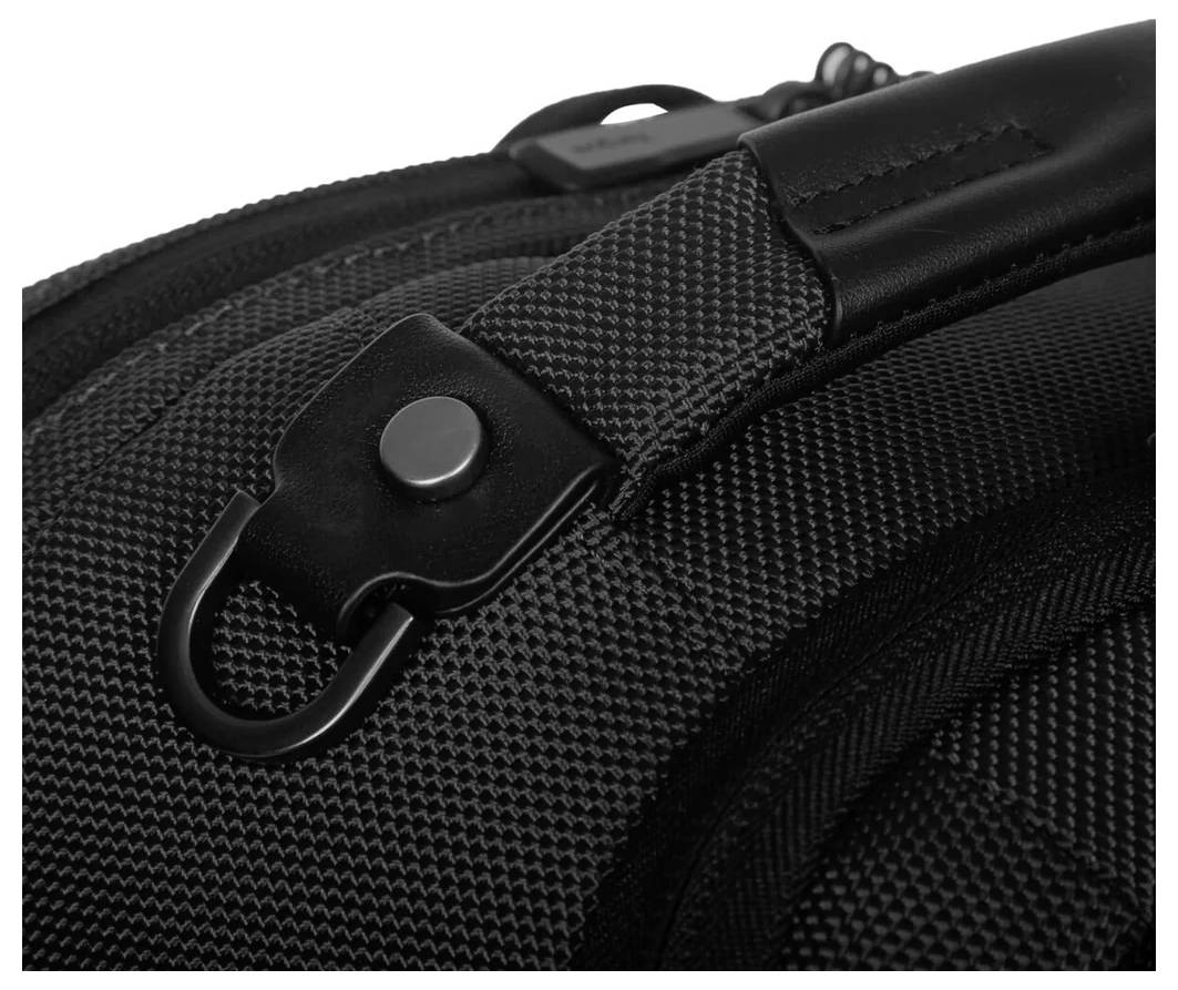 Zbliżenie czarnego plecaka z fakturowanej tkaniny z metalowym zapięciem na zatrzask przy jednym z pasków.