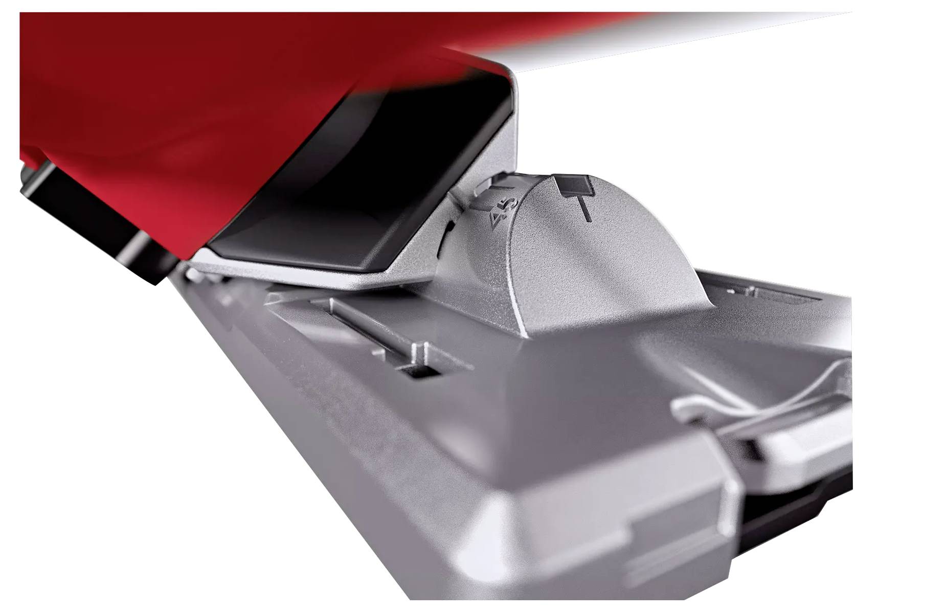 Srebrne mocowanie narciarskie, lekko zagięte, prezentuje mechanizm pięty i oznaczenia ustawień, częściowo zasłonięte czerwonym butem narciarskim.