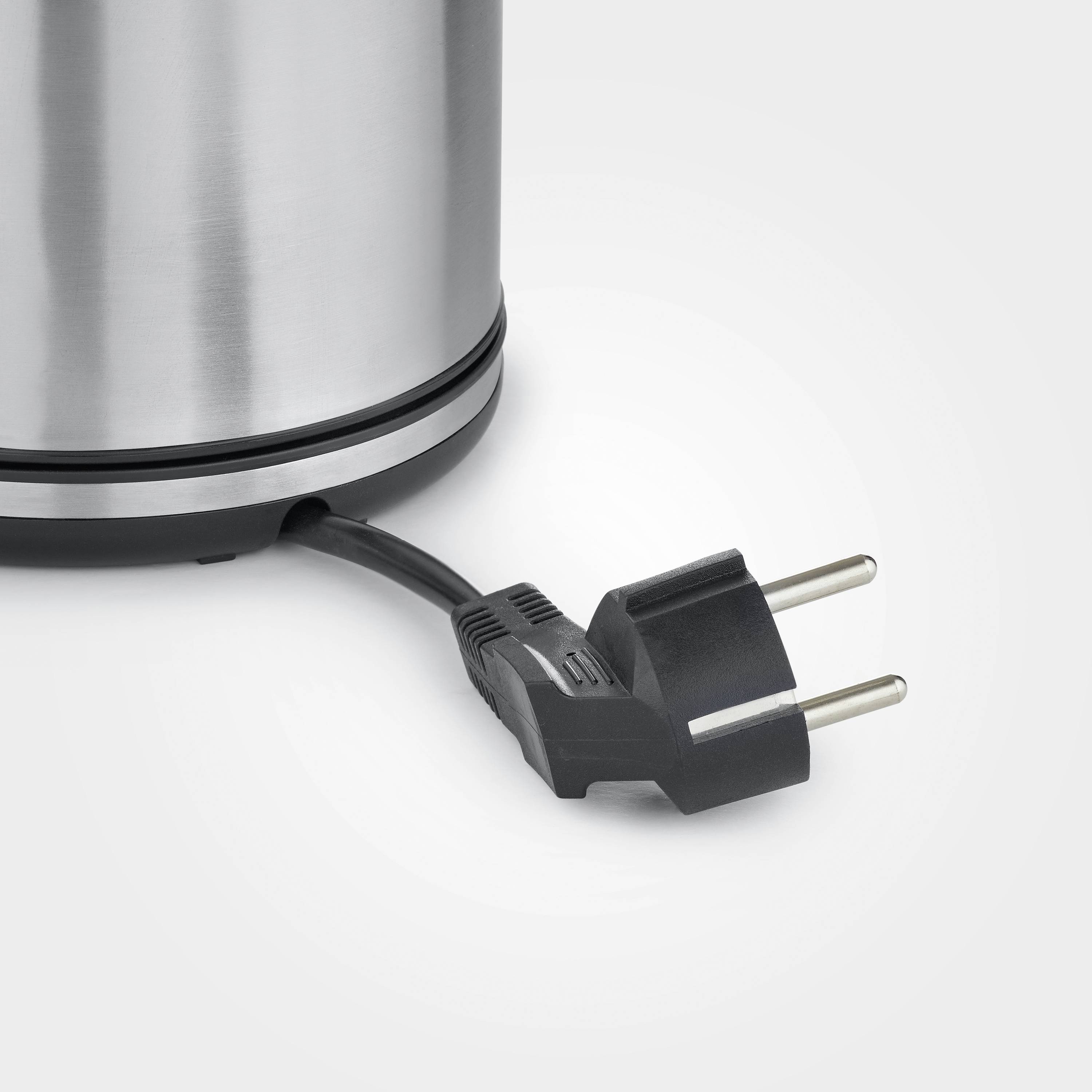 Okrągły, srebrny czajnik elektryczny z czarnym przewodem sieciowym i wtyczką, przedstawiony na jasnoszarym tle.