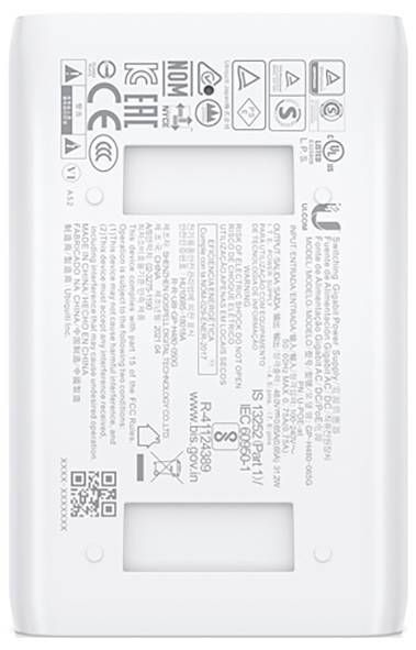 Prostokątne białe urządzenie z różnymi nadrukami technicznymi, oznaczeniami CE i ETL. Nadruki prezentują specyfikacje bezpieczeństwa i produktu.