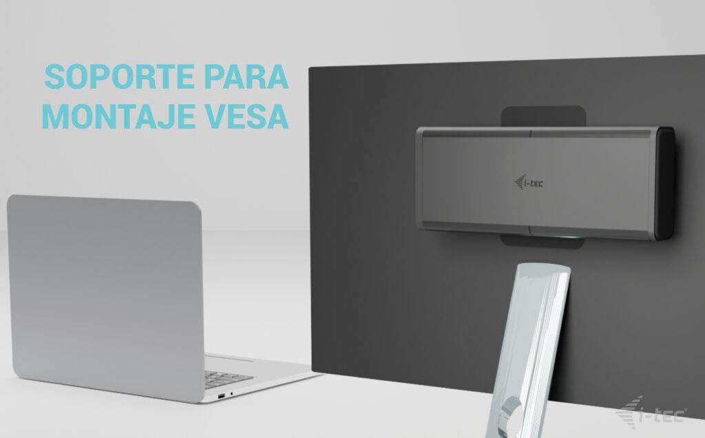 'UCHWYT MONTAŻOWY VESA' na szarym tle. Czarny uchwyt VESA zamontowany jest na ścianie. Obok niego stoi laptop.