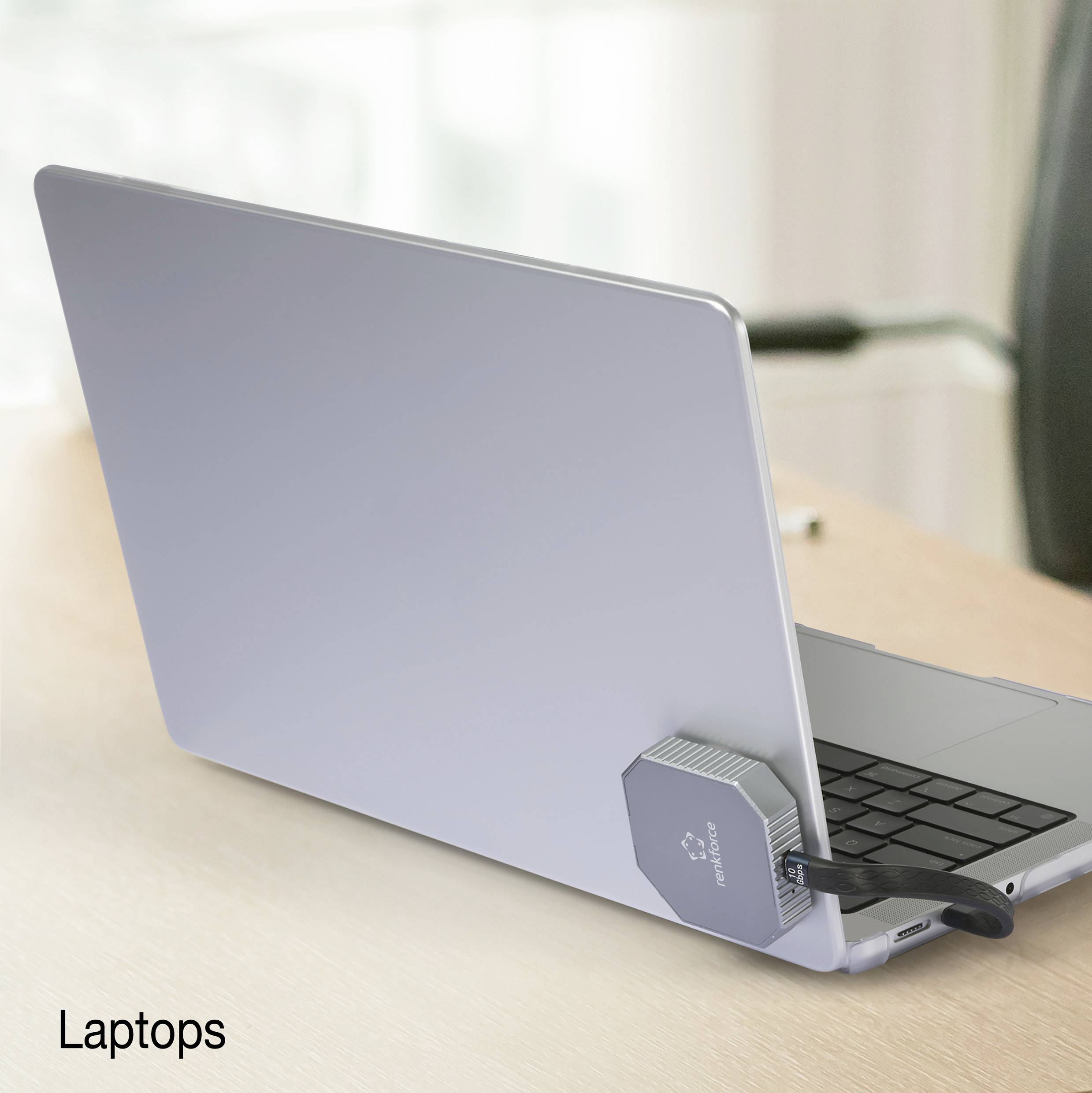 Otwarty laptop z włożonym pendrive'em w jednym z portów stoi na stole. W tle widać rozmyty fotel.