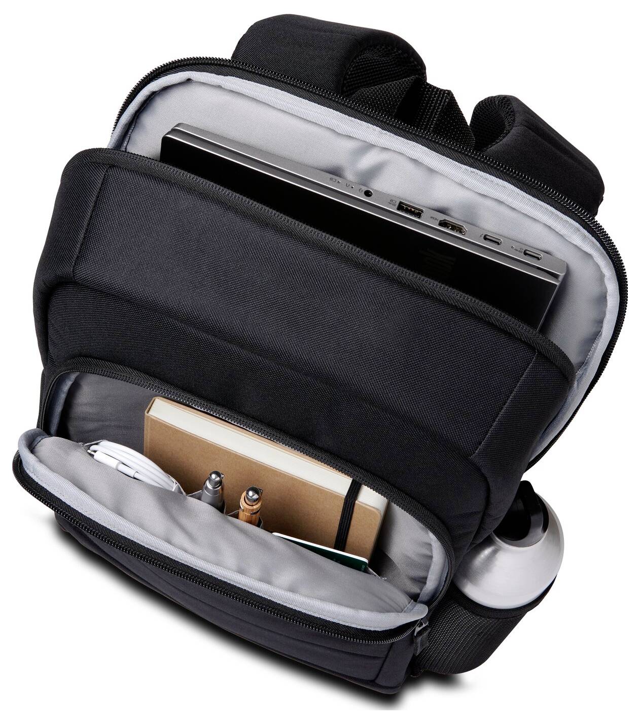 Otwarty czarny plecak ujawnia przegrodę na laptopa u góry oraz poniżej długopisy, notes i butelkę wody.