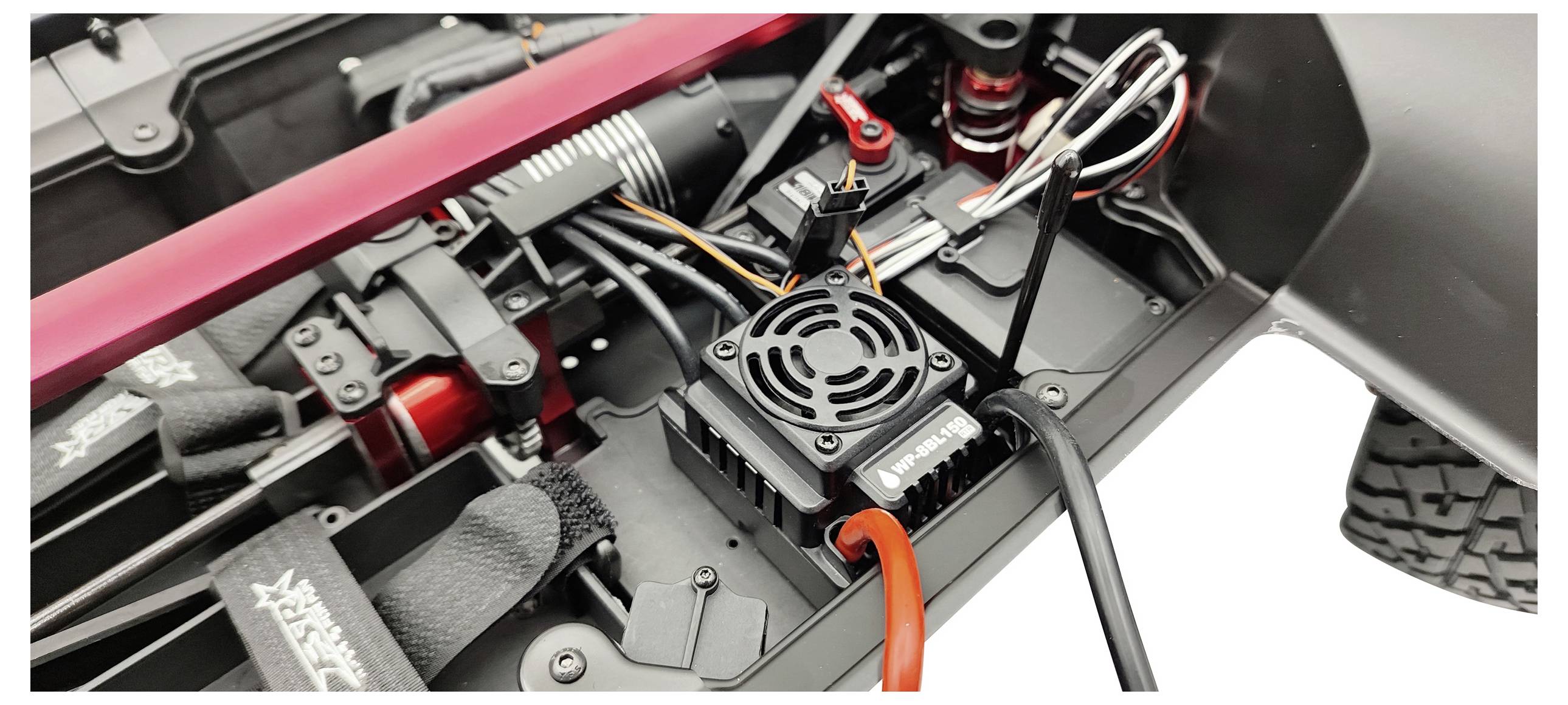 Zbliżenie zdalnie sterowanego samochodu przedstawia szczegóły elektroniki i części sterujących silnikiem, widoczne są kable i połączenia.