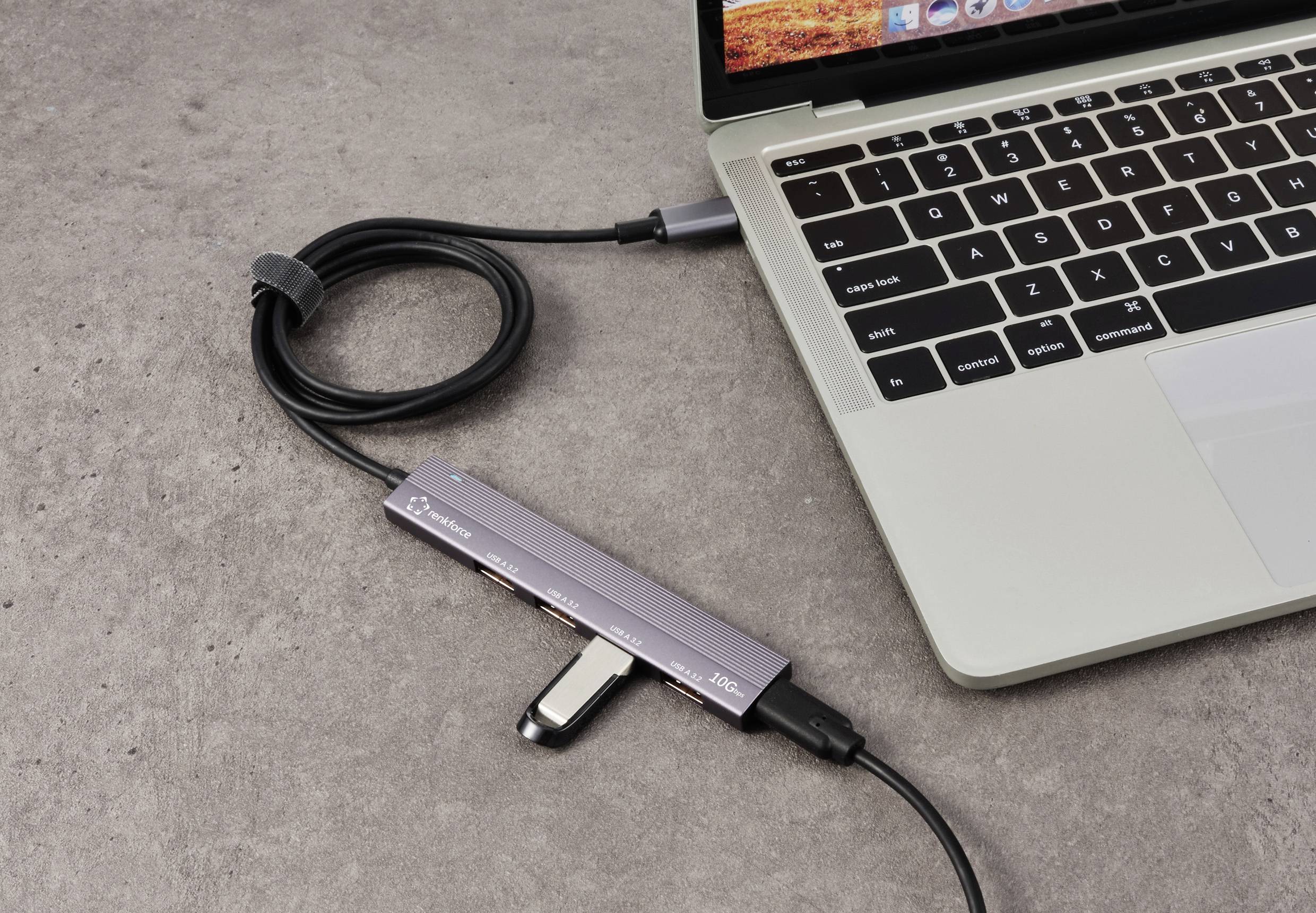 Laptop z podłączoną stacją dokującą USB. Stacja dokująca łączy kilka urządzeń kablowo z laptopem.