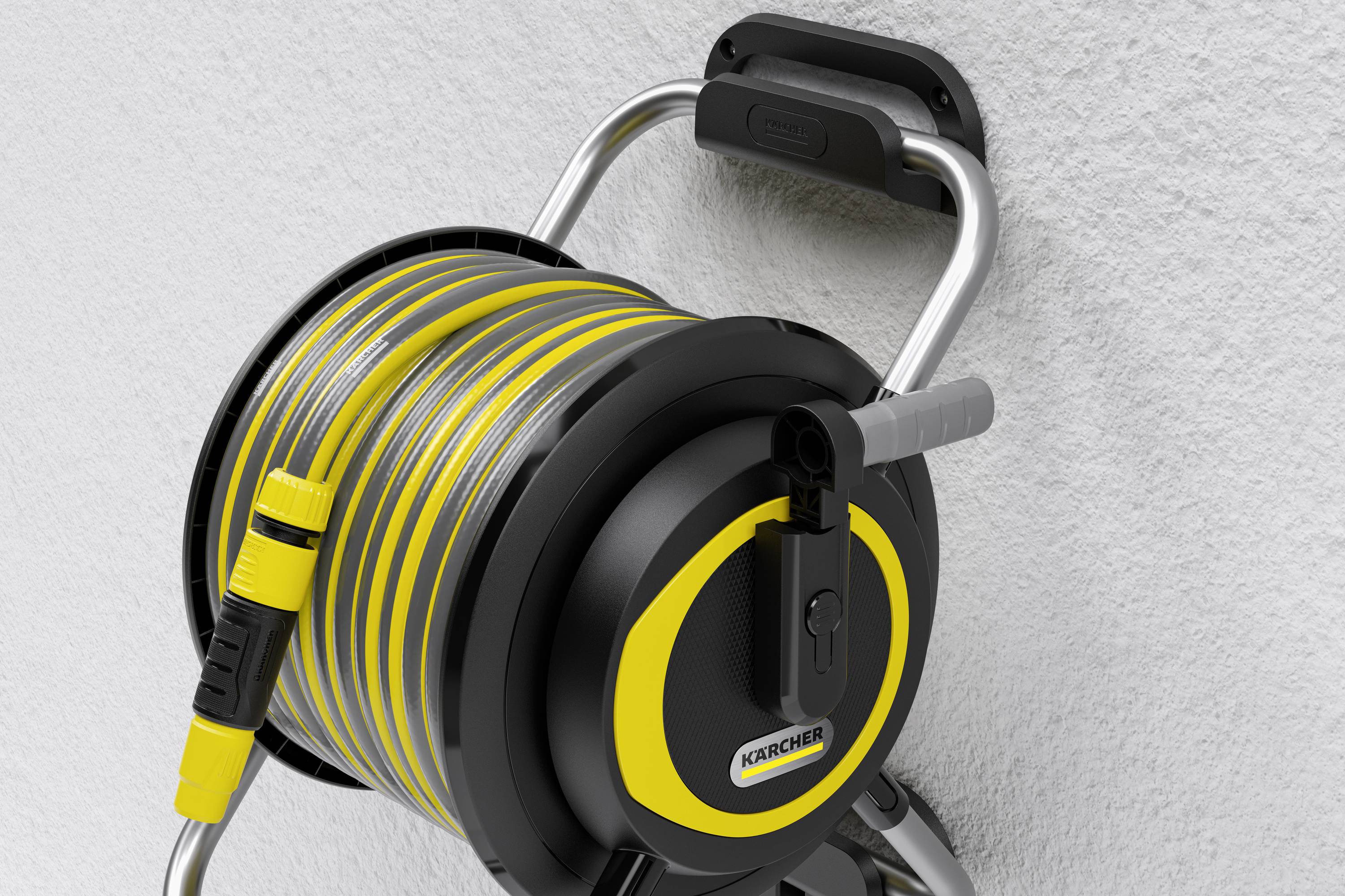 Ścienna szpula na wąż z żółtym, zrolowanym wężem ogrodowym i czarną rączką zamontowana na szarej ścianie.