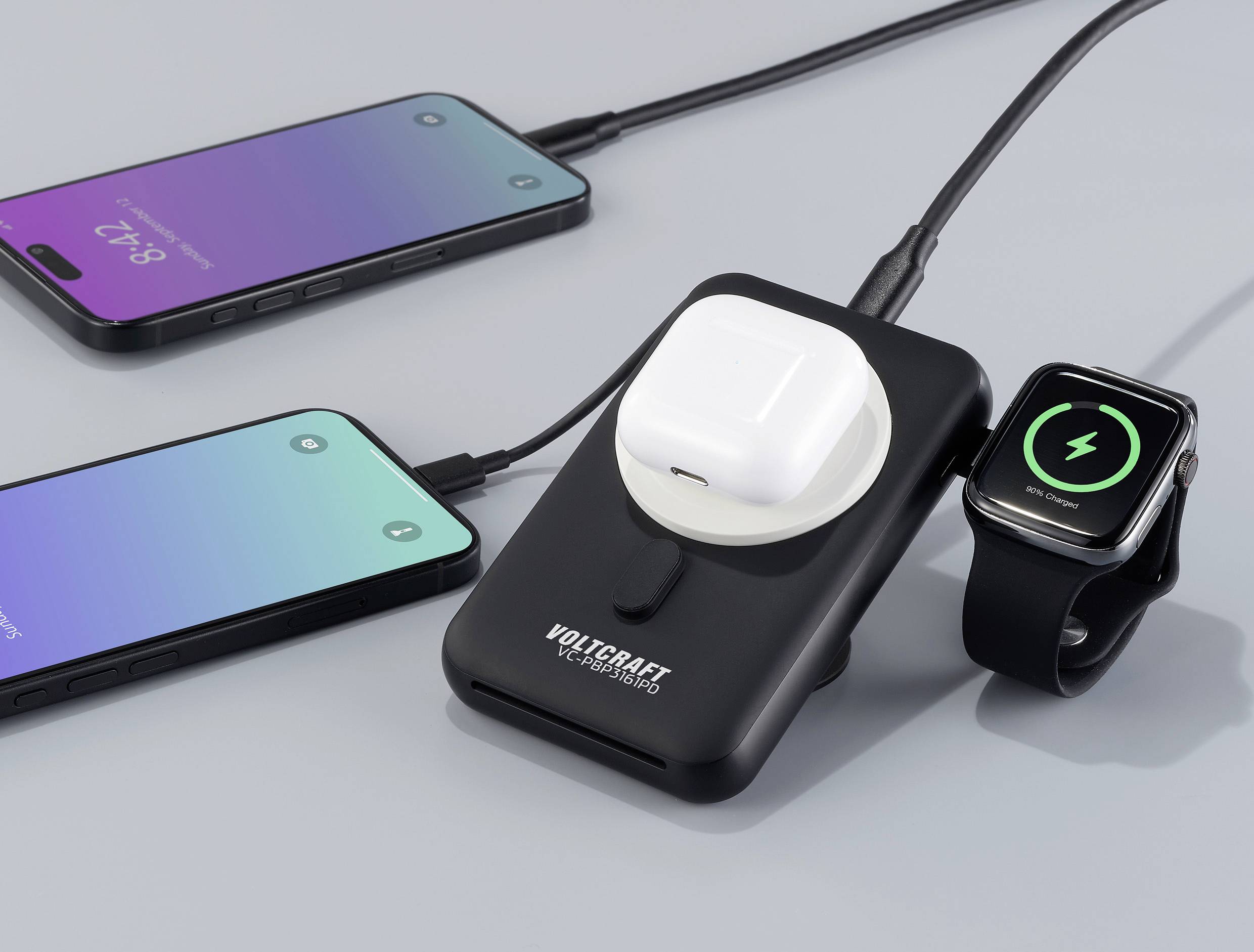 Wielofunkcyjna ładowarka z naładowanymi słuchawkami AirPods, smartwatchem i dwoma smartfonami. Postęp ładowania widoczny na ekranach.