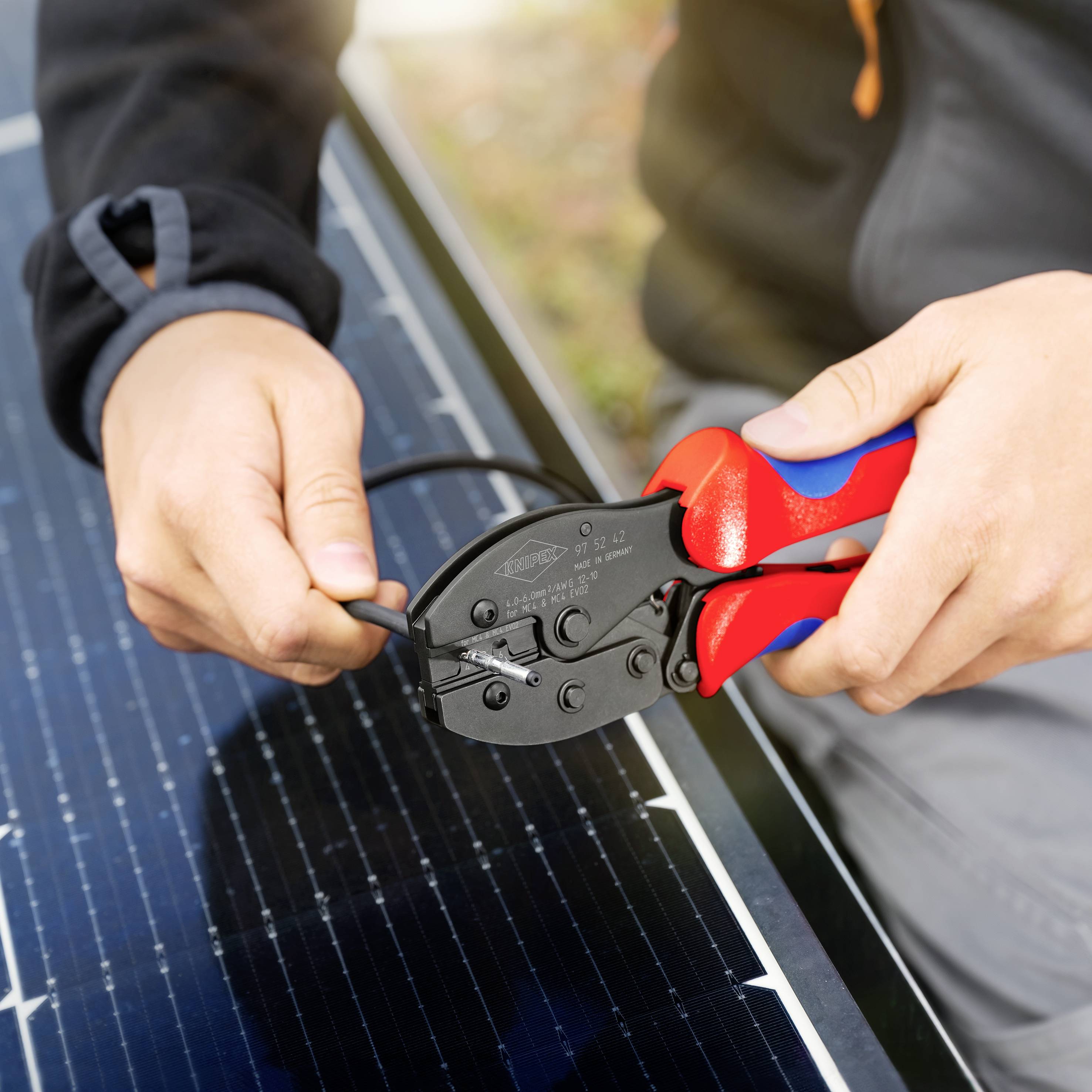 Osoba używa szczypiec do przymocowania przewodu do panelu słonecznego, symbolizując technikę i odnawialne źródła energii.