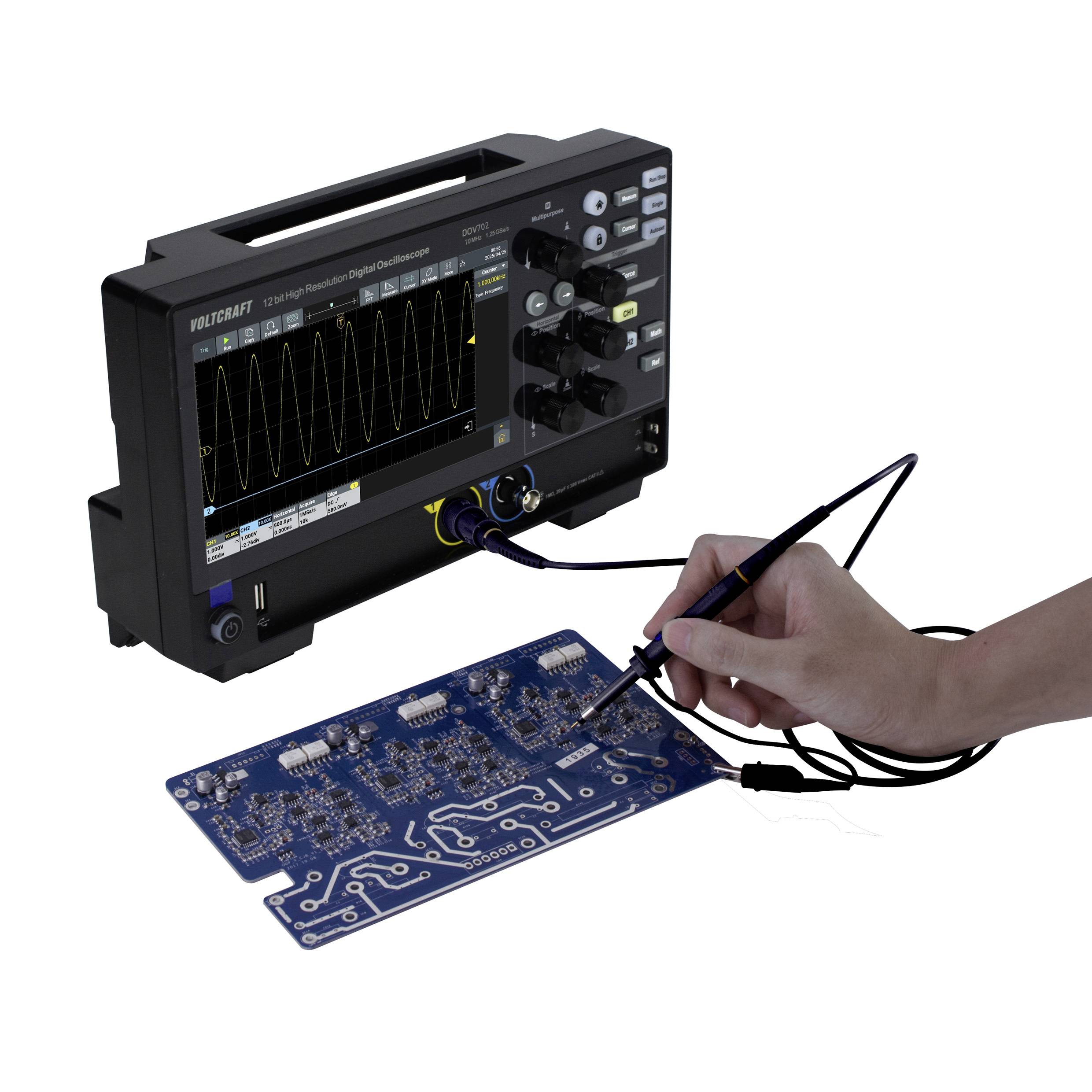 Jedna ręka przytrzymuje sondę pomiarową przy niebieskiej płytce drukowanej podłączonej do oscyloskopu. Ekran wyświetla przebieg fali.