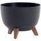 Czarny okrągły doniczka na trzech brązowych nóżkach, minimalistyczny design.