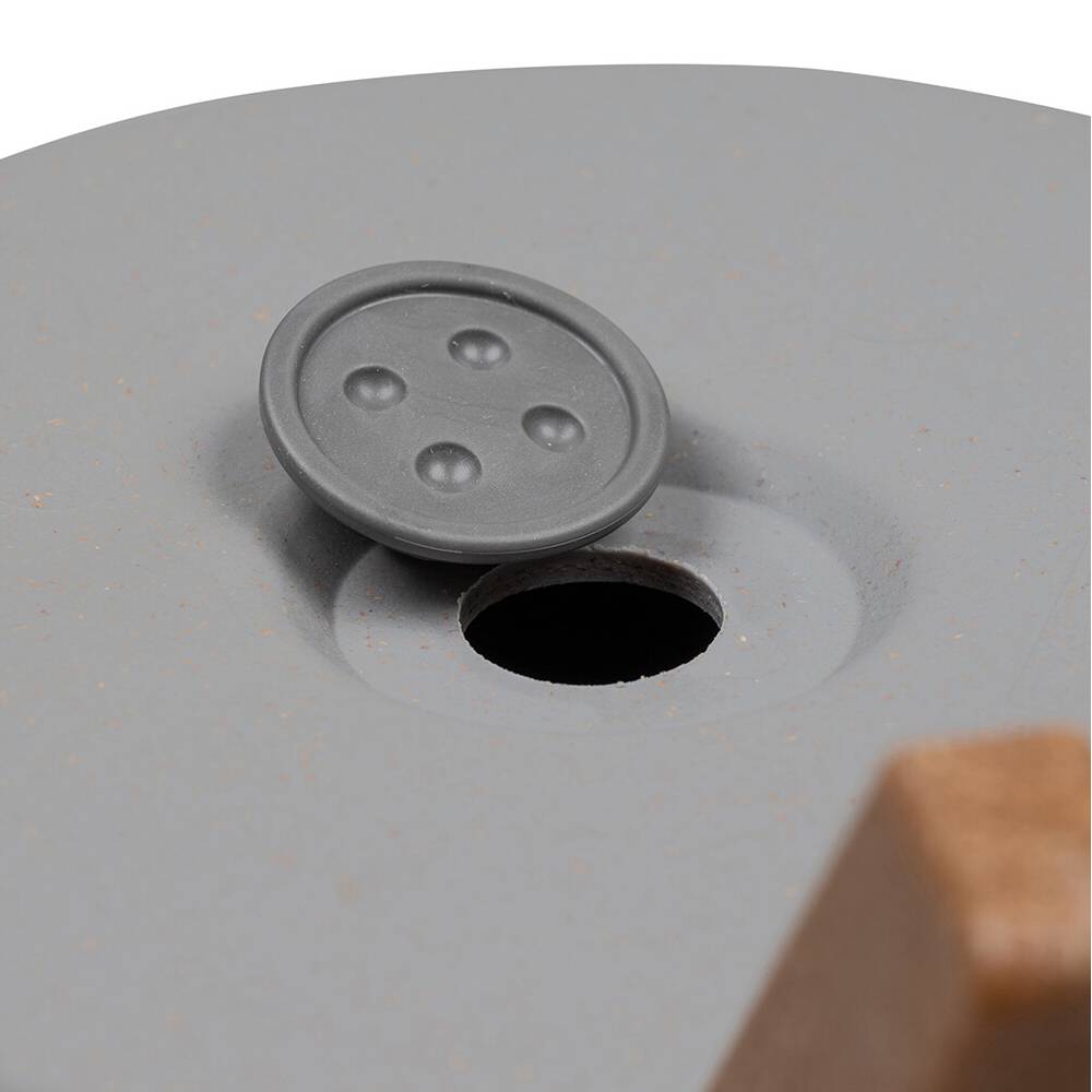 Szara, okrągła przykrywka leży częściowo obok okrągłego otworu w gładkiej, płaskiej powierzchni.