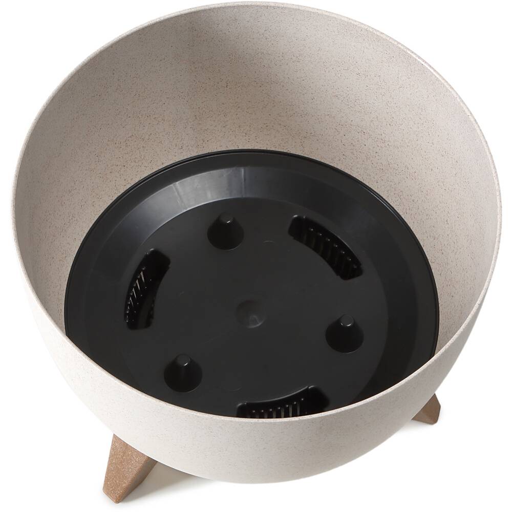 Okrągła, beżowa doniczka z czarnym wkładem, stojąca na trzech brązowych drewnianych nogach. Idealna do użytku wewnątrz i na zewnątrz.