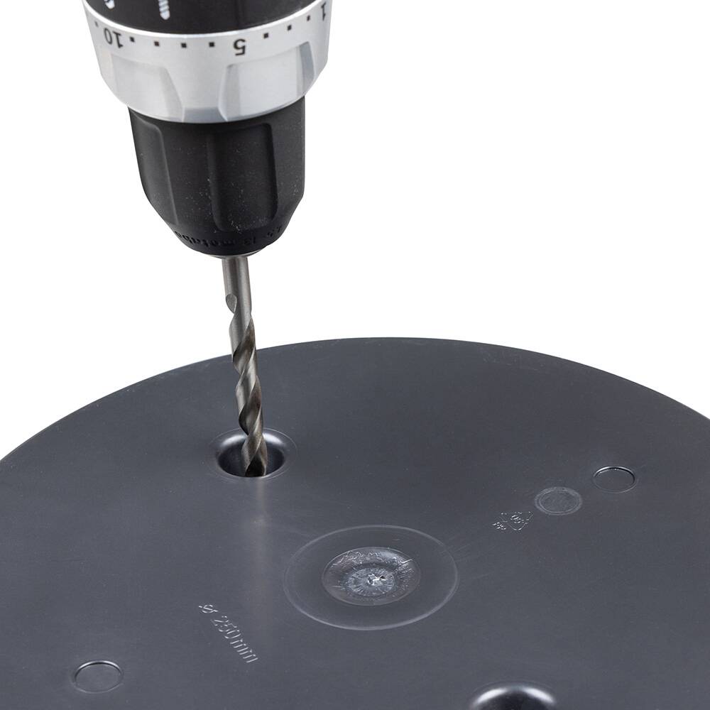 Wiertarka wierci otwór w czarnej plastikowej powierzchni. Wiertło jest ostre i metalowe.