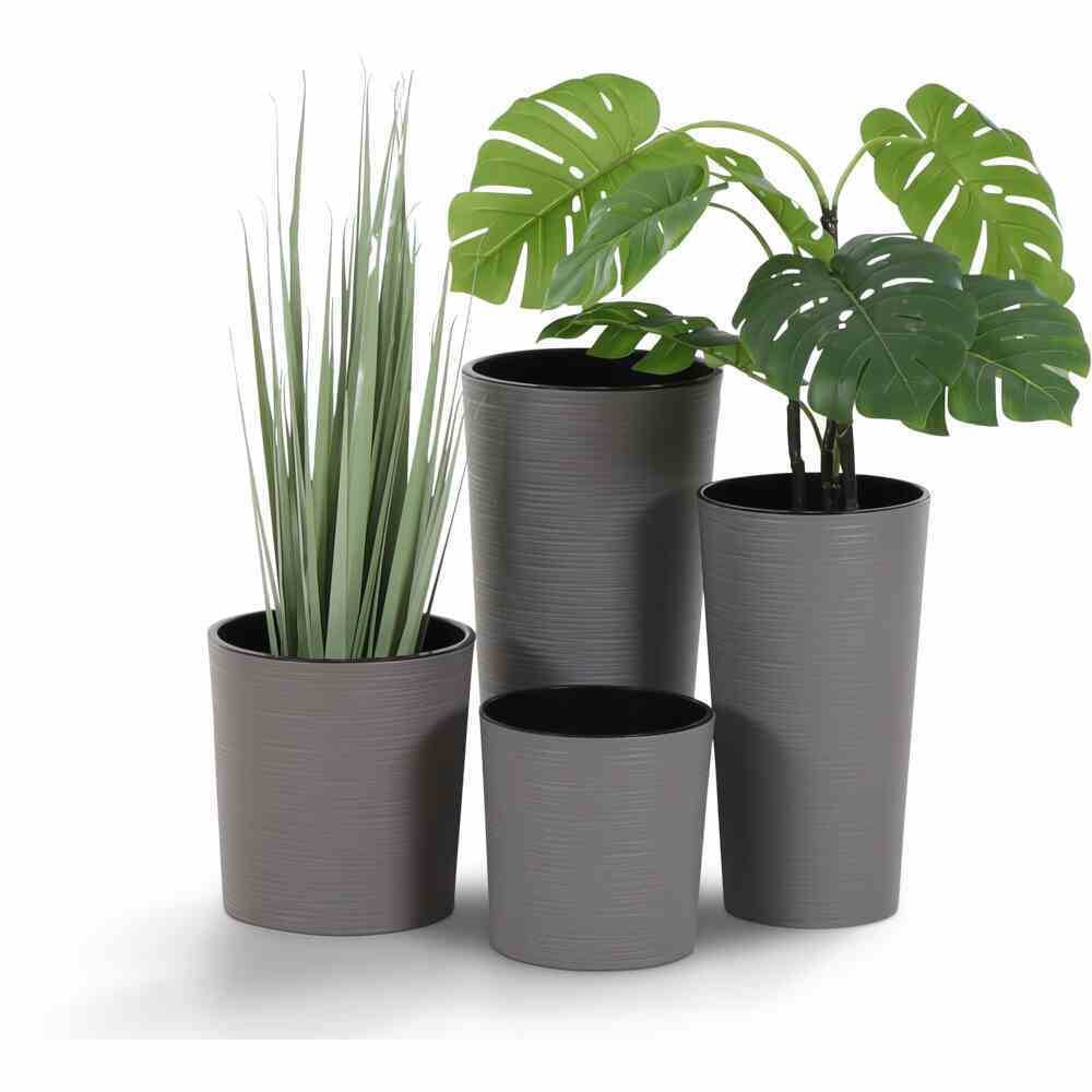 Cztery doniczki z roślinami: po lewej wysokie trawy, po prawej duże zielone liście. Dwie puste doniczki z przodu, o różnych rozmiarach.