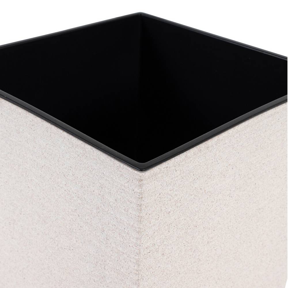 Biały, kwadratowy wazon o gładkiej powierzchni z czarnym wnętrzem. Stoi na płaskiej powierzchni.