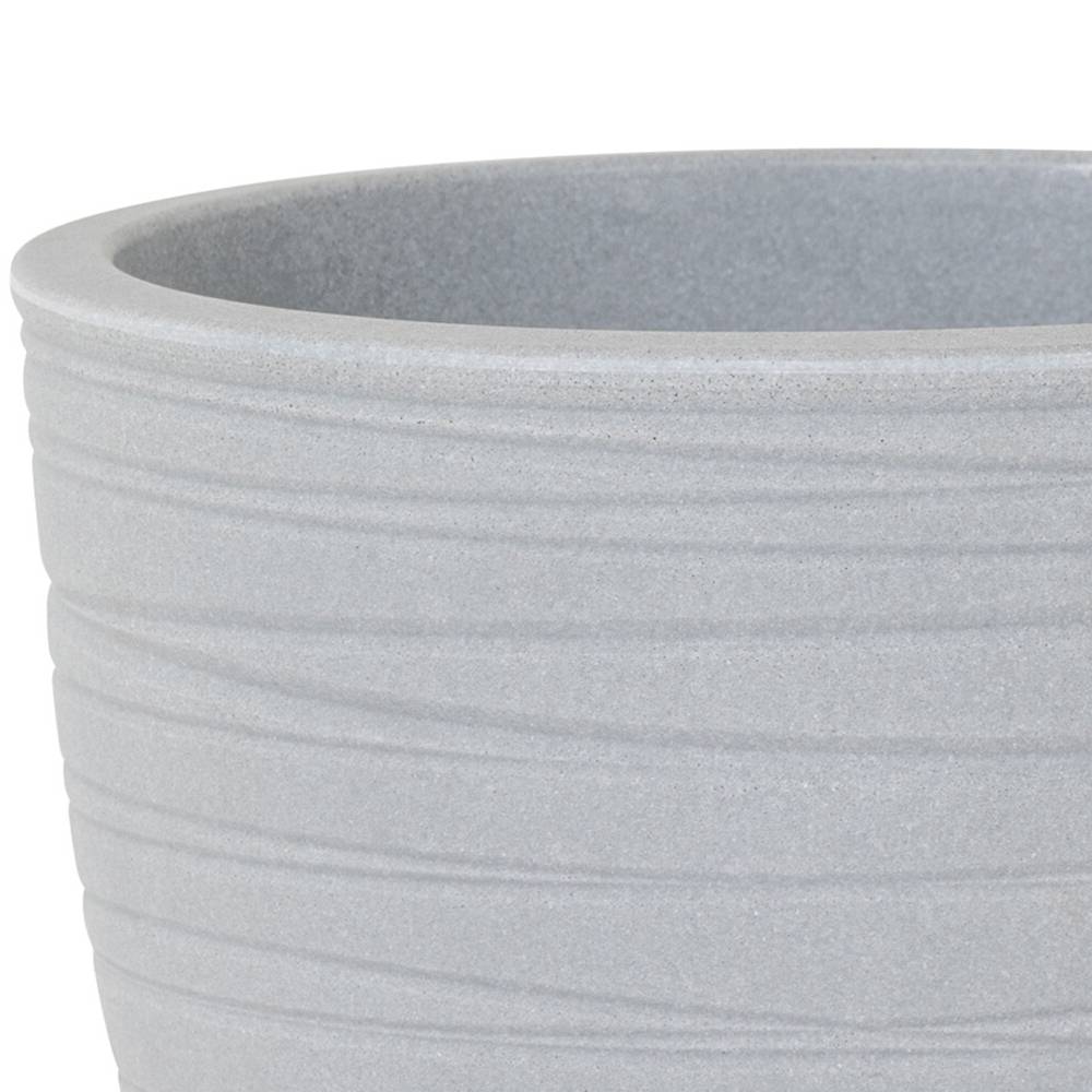 Szczegółowe, bliskie ujęcie szarego ceramicznego garnka z delikatnymi, poziomymi żłobieniami na powierzchni.