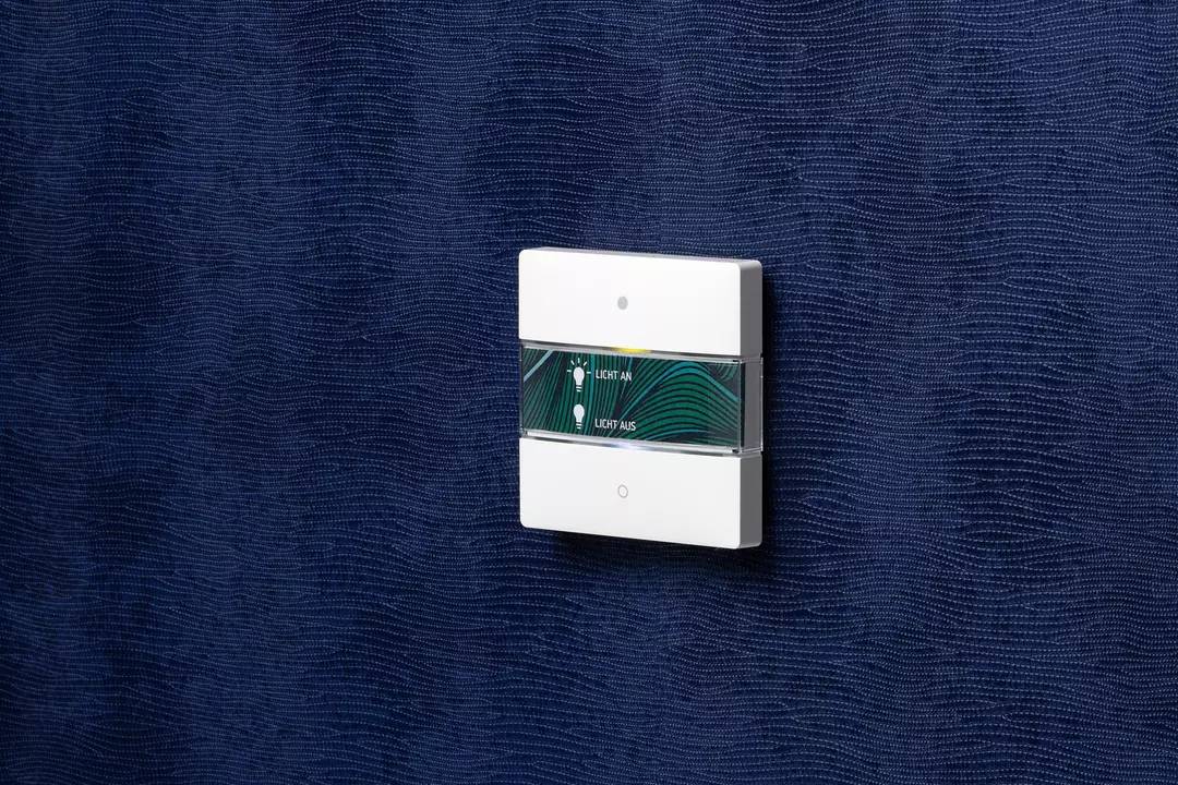 Włącznik światła na niebieskiej ścianie z dwoma przyciskami: jeden do włączania, drugi do wyłączania światła.