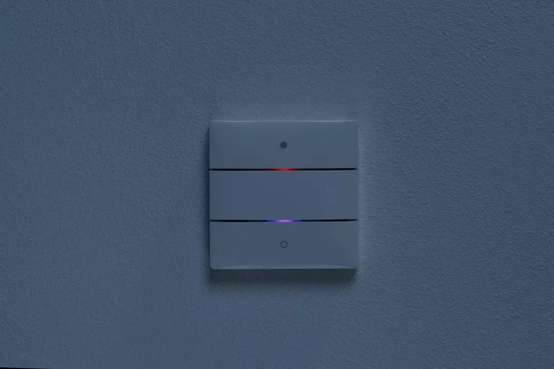 Przełącznik z dwoma przyciskami na białej ścianie, świecą czerwona i niebieska dioda LED.