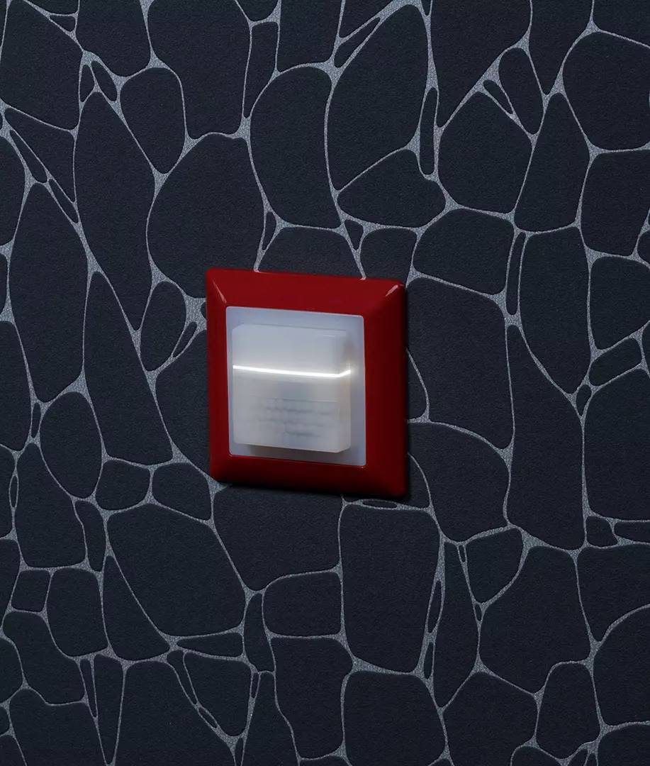 Włącznik światła z czerwoną ramką na ciemnym tle we wzór przypominający sieć.
