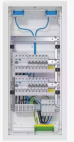 Otwarty rozdzielnik elektryczny z kablami i bezpiecznikami. Widoczne są różne kolory przewodów, w tym niebieski, czarny oraz biało-żółty.