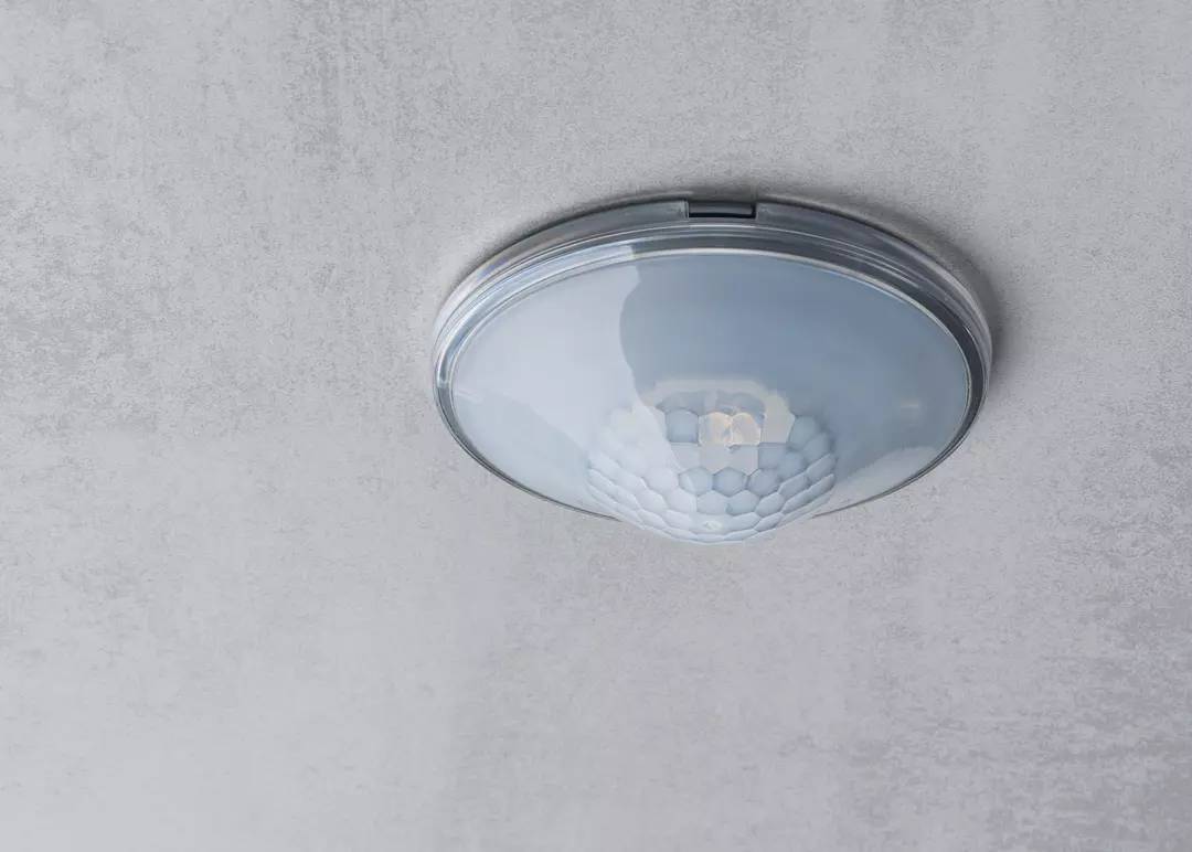 Lampa sufitowa z wbudowanym czujnikiem ruchu na szarym suficie.