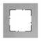 Srebrna, kwadratowa ramka z prostokątnym otworem pośrodku, prawdopodobnie przeznaczona do zamontowania włącznika światła lub gniazdka elektrycznego.