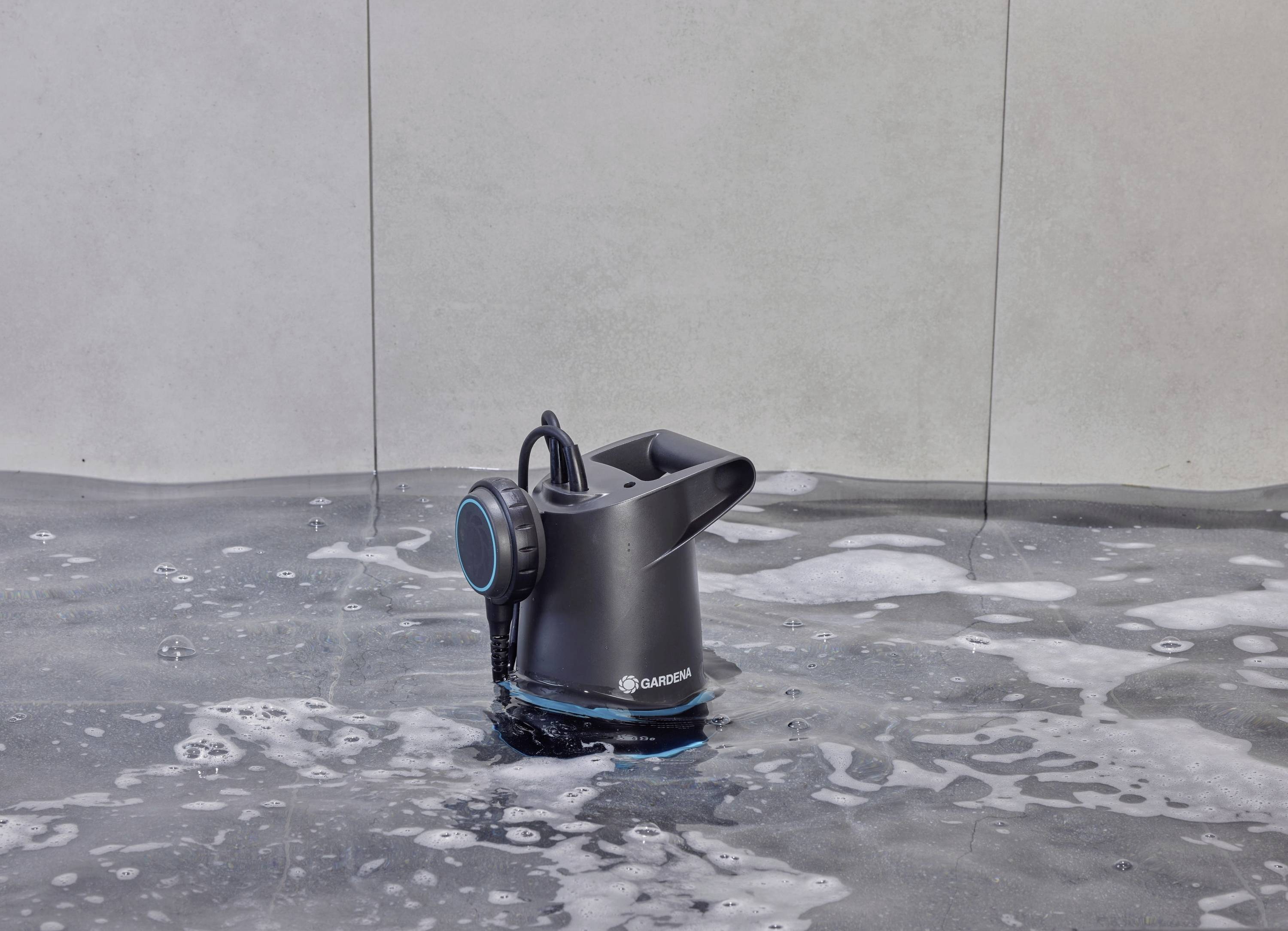 Czarna pompa zanurzeniowa stoi w wodzie, otoczona płaskimi falami i pianą.