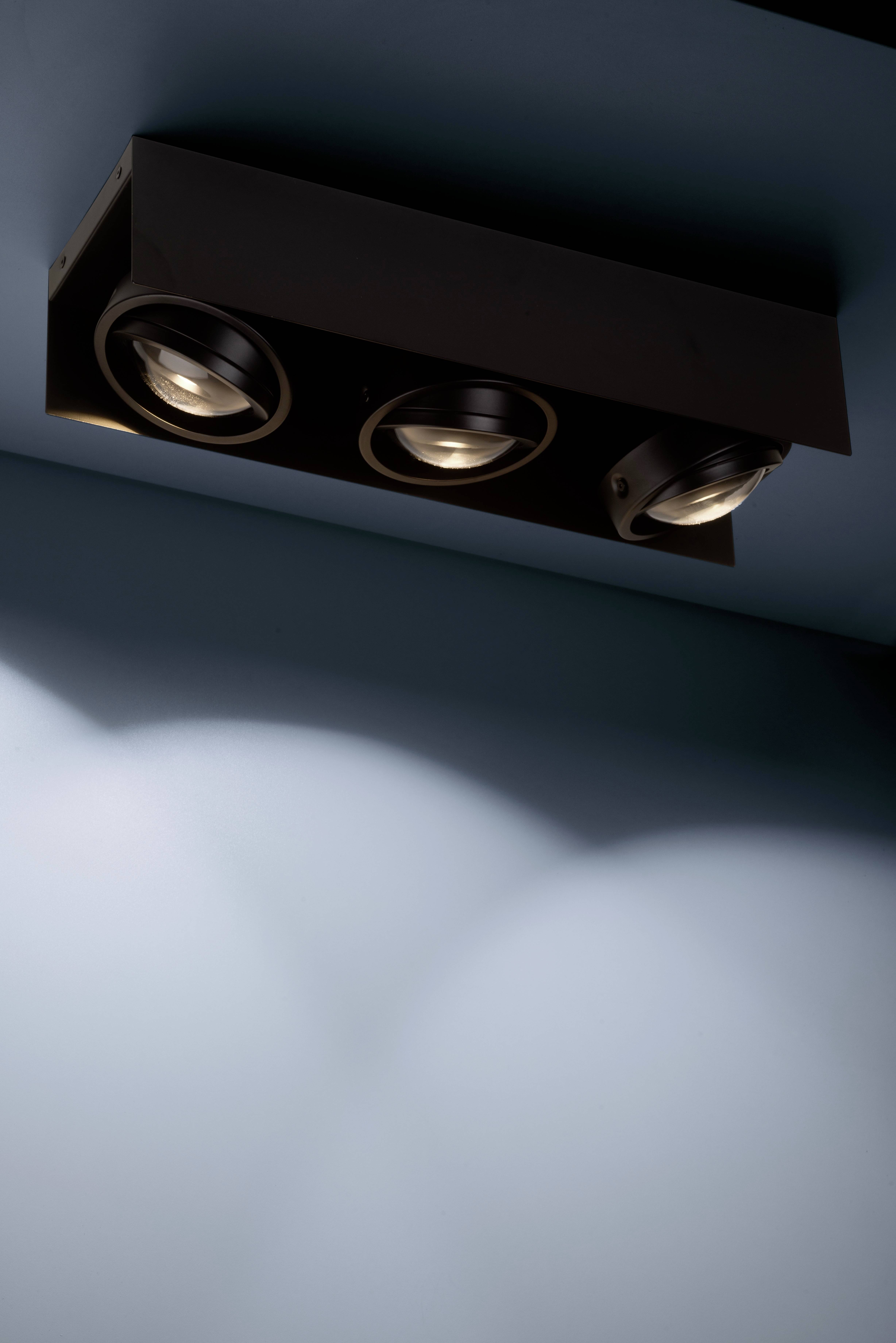 Trzy wbudowane reflektory sufitowe oświetlają niebieski pokój, tworząc delikatne cienie na ścianie.