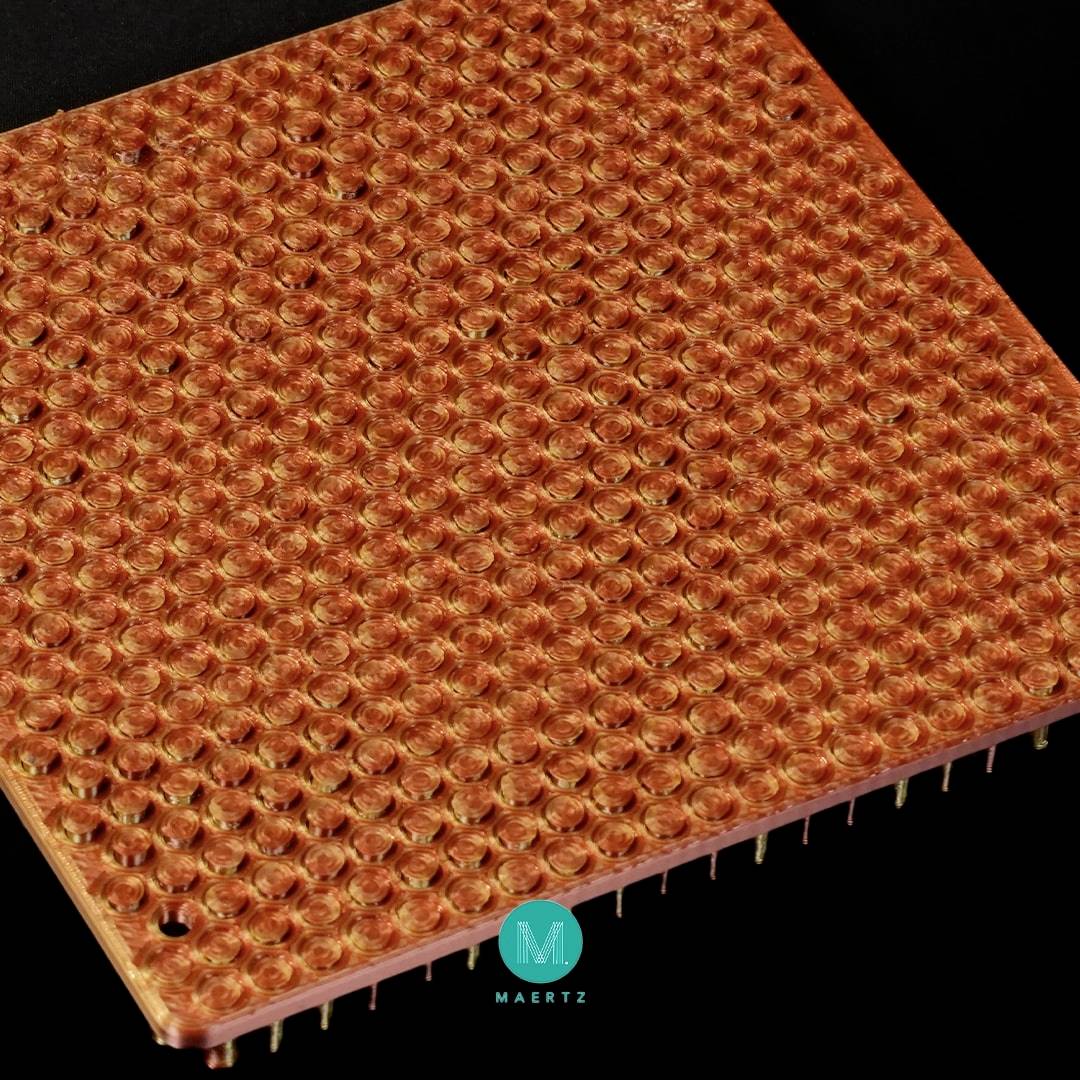 Powiększony widok spodu procesora komputerowego ze złotymi pinami ułożonymi w regularnym wzorze siatki.