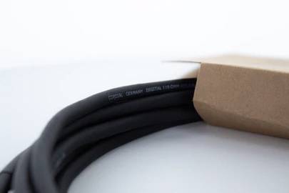 Czarny kabel z napisem 'Germany Digital 110 Ohm', częściowo zapakowany w kartonowe opakowanie, na jasnym tle.