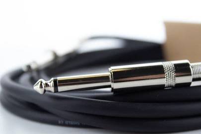 Czarny kabel audio z srebrnym wtykiem jack leży zwinięty na stole.