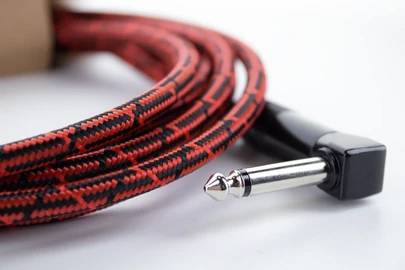 Czerwony, pleciony kabel audio z wtyczką kątową jack na białej powierzchni.
