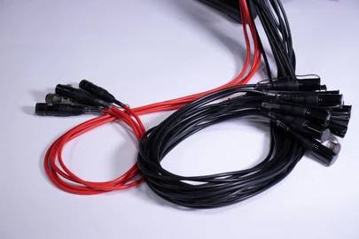 Czarne i czerwone kable audio na białym tle, splecione ze sobą.