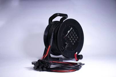 Czarny, zwinięty kabel przedłużający z wieloma gniazdami elektrycznymi na rolce leży na białym tle.