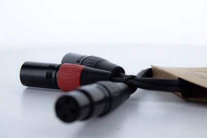 Trzy czarne kable audio z wtykami na białym tle. Jeden wtyk posiada czerwony pierścień, pozostałe są bez oznaczenia.